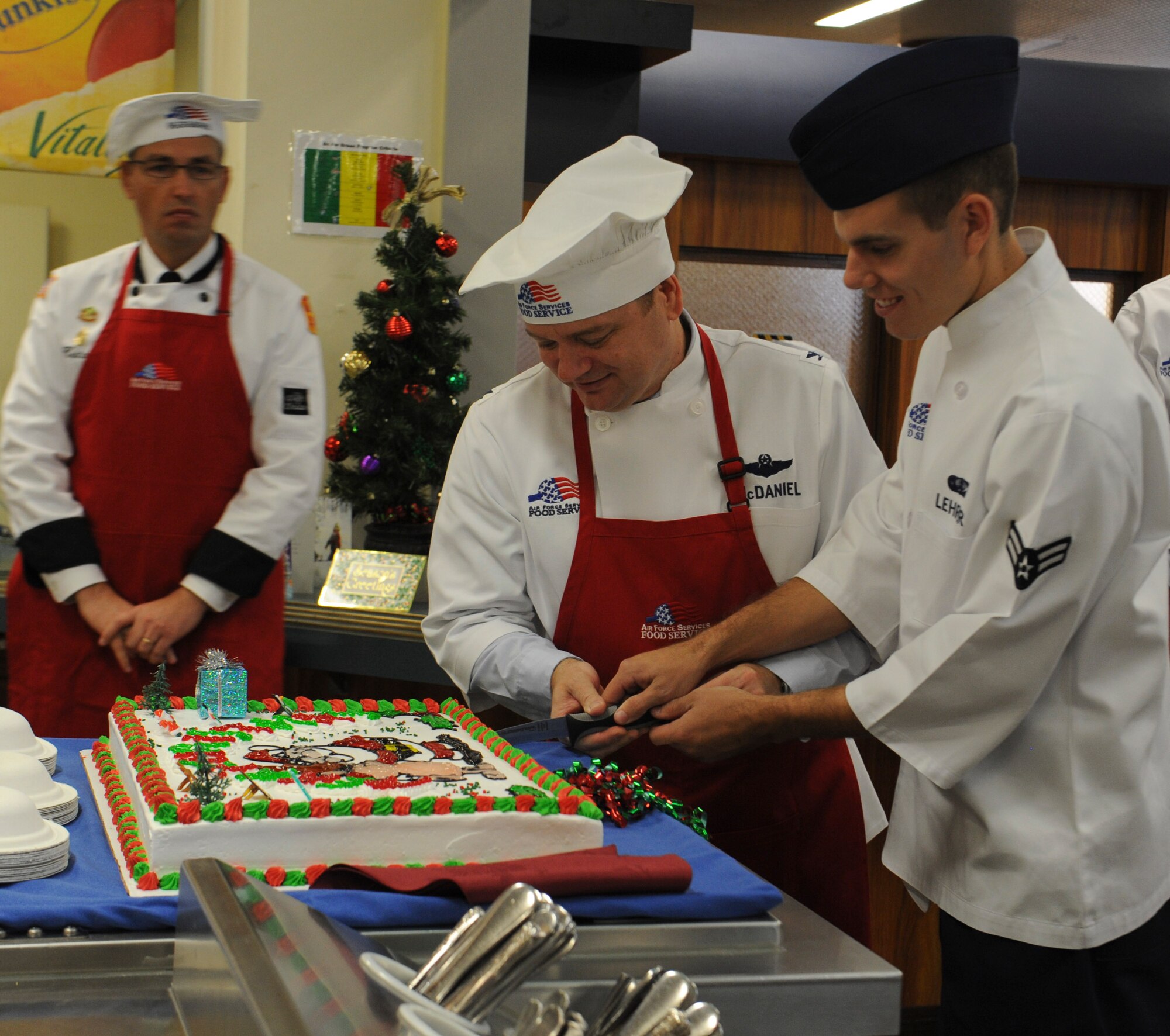 U.S. Air Force Col. Brian McDaniel, 18th Wing vice commander, cuts a cake with Airman 1st Class Joseph Lehrer, a member of the 18th Force Support Squadron, during the Christmas meal opening ceremony at the Marshall Dining Facility on Kadena Air Base, Japan, Dec. 25, 2012. The meal is an annual tradition where Kadena's leadership gives back to the Airmen by serving them various Christmas dishes and wishing them a happy holiday. (U.S. Air Force photo/Airman 1st Class Malia Jenkins)