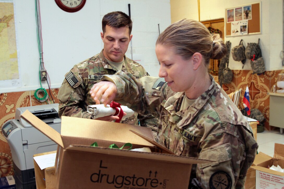 U.S. Navy Lt. j.g. Laura Cook, right, presents a Christmas gift to U.S. Navy Petty Officer 1st Class Daniel Baudin, left, on Forward Operating Base Farah, Afghanistan, Dec. 24, 2012. Cook, a physician assistant, and Baudin, an intelligence specialist, are assigned to Provincial Reconstruction Team Farah.