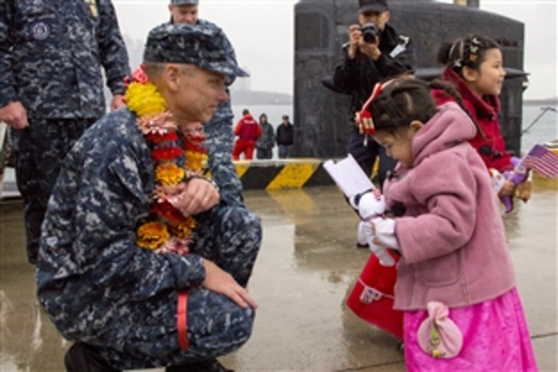 U.S. Navy Cmdr. Jeff Bernard, commanding officer of the attack submarine USS La Jolla, gives small stuffed animals to the daughters of South Korean sailors in Busan, South Korea, Dec. 21, 2012. The La Jolla is in Busan for a scheduled port visit during its deployment to the western Pacific. 