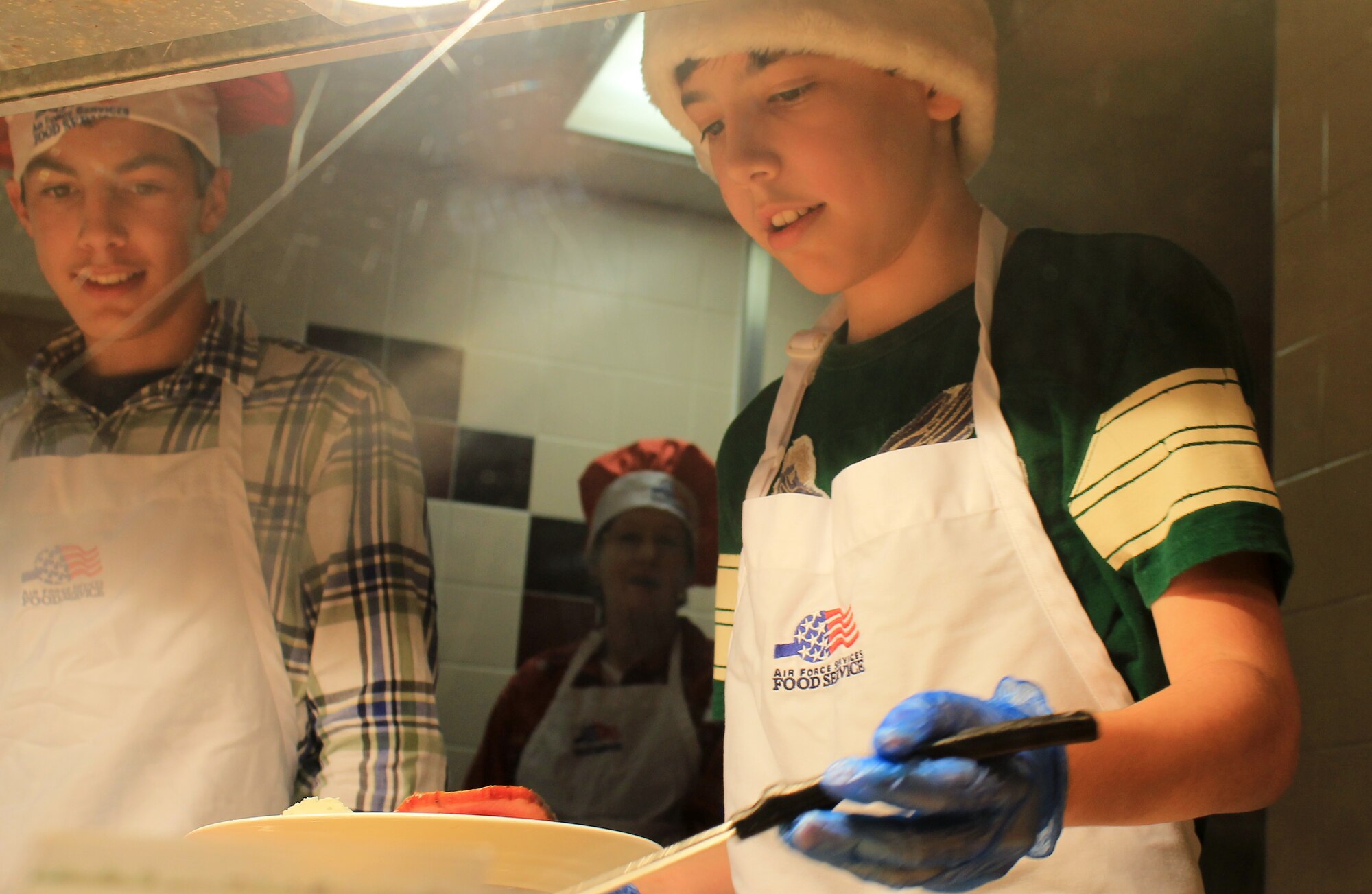 Drew (left) and Jack Kulas, sons of Col. Christopher Kulas, 100th Air Refueling Wing commander, serve some food at the Gateway Dining Facility on Dec. 25, 2012, at RAF Mildenhall, England. The dining facility served a special holiday meal for all authorized patrons from 11 a.m. – 4 p.m. The meal included a shrimp cocktail appetizer, ham, turkey, roast beef and stuffing among a wide variety of other traditional dishes. Throughout the day, various commanders, chief master sergeants, first sergeants and other leaders from Team Mildenhall served the meal to dining facility customers. (U.S. Air Force photo by Capt. Jason Smith/Released)