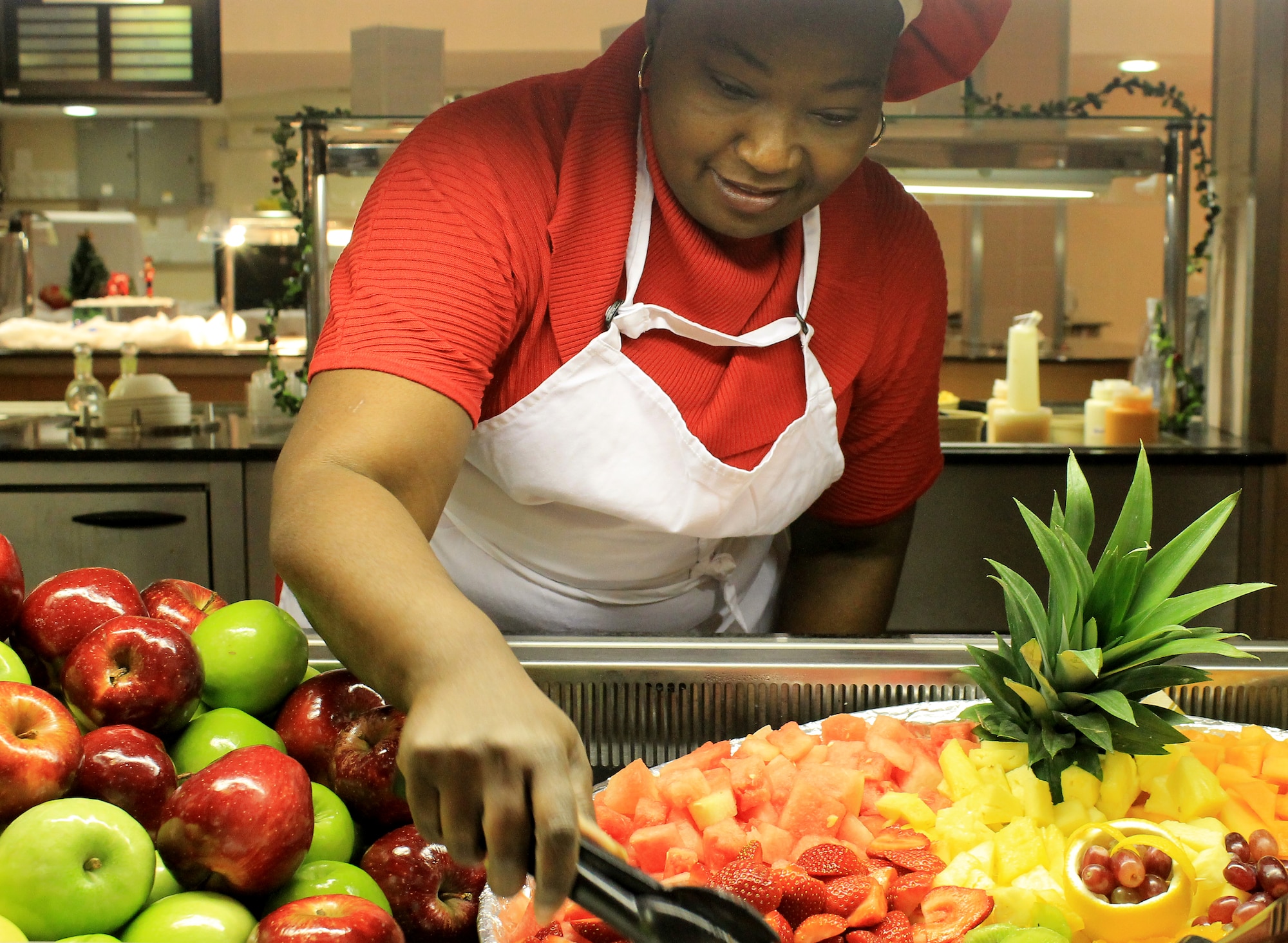 Kathy Taylor, 100th Force Support Squadron employee and San Antonio native, arranges fruit at the Gateway Dining Facility on Dec. 25, 2012, at RAF Mildenhall, England. The dining facility served a special holiday meal for all authorized patrons from 11 a.m. – 4 p.m. The meal included a shrimp cocktail appetizer, ham, turkey, roast beef and stuffing among a wide variety of other traditional dishes. Throughout the day, various commanders, chief master sergeants, first sergeants and other leaders from Team Mildenhall served the meal to dining facility customers. (U.S. Air Force photo by Capt. Jason Smith/Released)