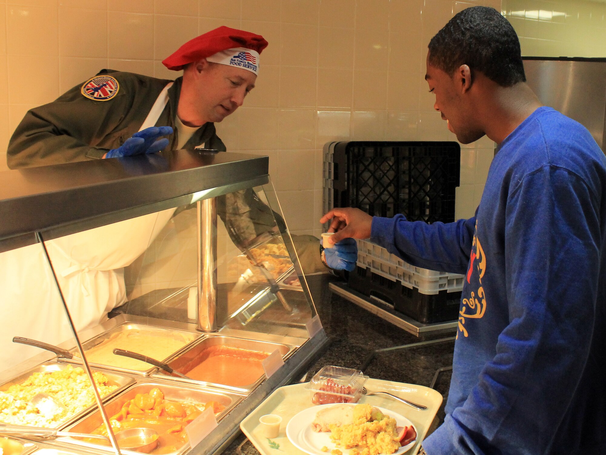 Brig. Gen. Jon A. Norman, Director to the United States Air Forces in Europe – United Kingdom, serves Airman 1st Class Laurentis Crowson, 352nd Special Operations Squadron and Burlington, N.C., native, at the Gateway Dining Facility on Dec. 25, 2012, at RAF Mildenhall, England. The dining facility served a special holiday meal for all authorized patrons from 11 a.m. – 4 p.m. The meal included a shrimp cocktail appetizer, ham, turkey, roast beef and stuffing among a wide variety of other traditional dishes. Throughout the day, various commanders, chief master sergeants, first sergeants and other leaders from Team Mildenhall served the meal to dining facility customers. (U.S. Air Force photo by Capt. Jason Smith/Released)