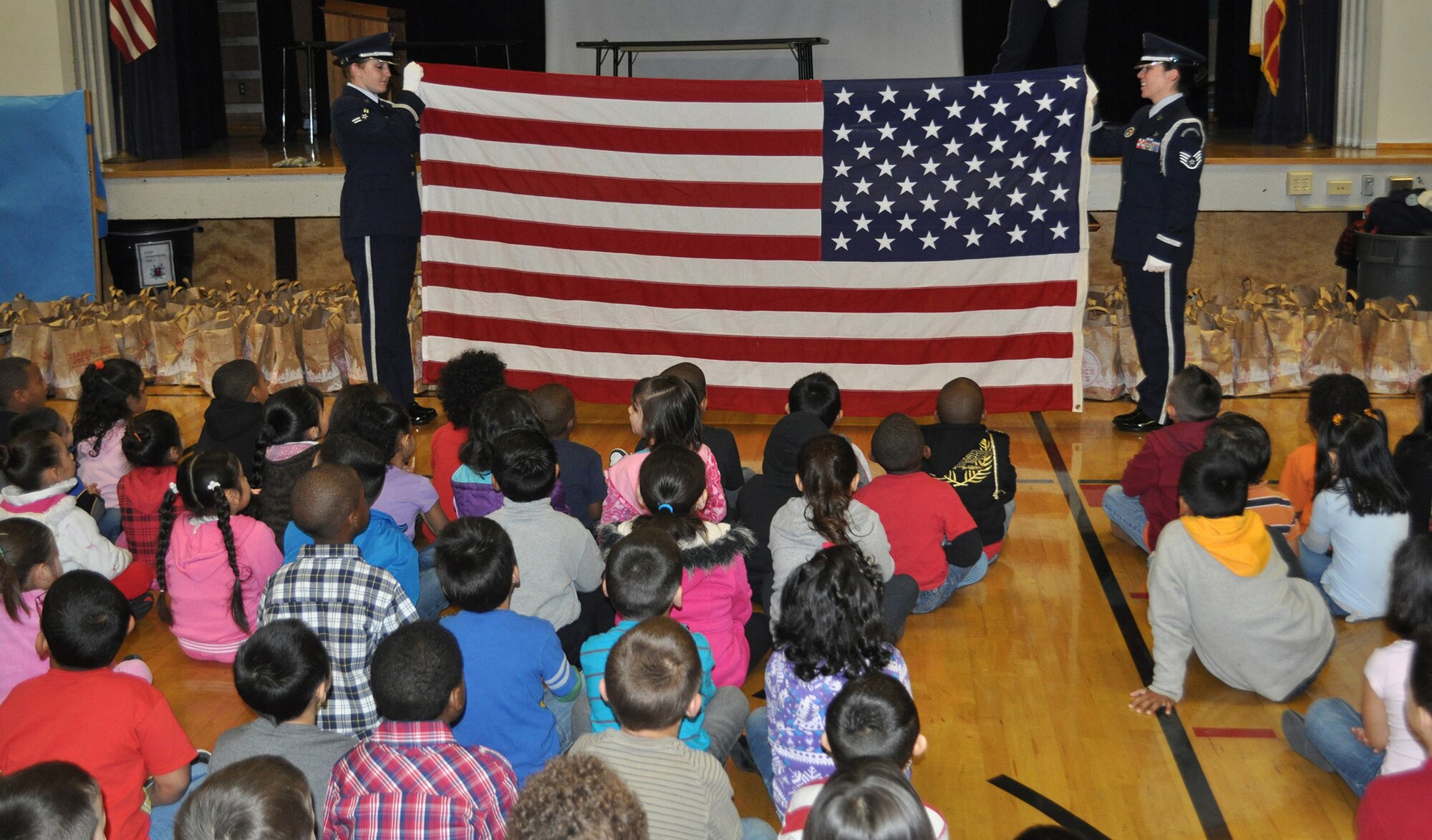 TRAVIS AIR FORCE BASE, Calif. -- Reserve Airmen with the Travis Air Force Base Honor Guard demonstrate how to fold the flag for these kindergarteners at Cleo Gordon Elementary School in Fairfield. The Honor Guard were visiting the children with "Santa" and his Travis elves, as part of Operation Teddy Bear. Every year, reservists from the 349th Air Mobility Wing work with local donors to put together gift bags, including Teddy bears, for kindergarten children that otherwise wouldn't have very happy holidays. This year, the Airmen visited four schools, spreading joy to those less fortunate than we are. (U.S. Air Force photo/Senior Master Sgt. Ellen Hatfield) 