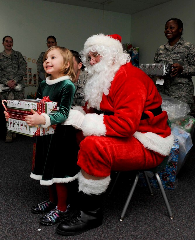 Santa Claus presents a gift to Doris Lowe, a four year old child enrolled in the Youth and Family Services Child Care program, during the 28th Operations Group Angel Tree gift program in Rapid City, S.D., Dec. 18, 2012. Thirty Ellsworth Airmen volunteered to help Santa hand out presents and candy canes to each child in the program. (U.S. Air Force photo by Airman 1st Class Anania Tekurio/Released)