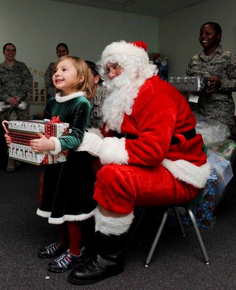Santa Claus presents a gift to Doris Lowe, a four year old child enrolled in the Youth and Family Services Child Care program, during the 28th Operations Group Angel Tree gift program in Rapid City, S.D., Dec. 18, 2012. Thirty Ellsworth Airmen volunteered to help Santa hand out presents and candy canes to each child in the program. (U.S. Air Force photo by Airman 1st Class Anania Tekurio/Released)