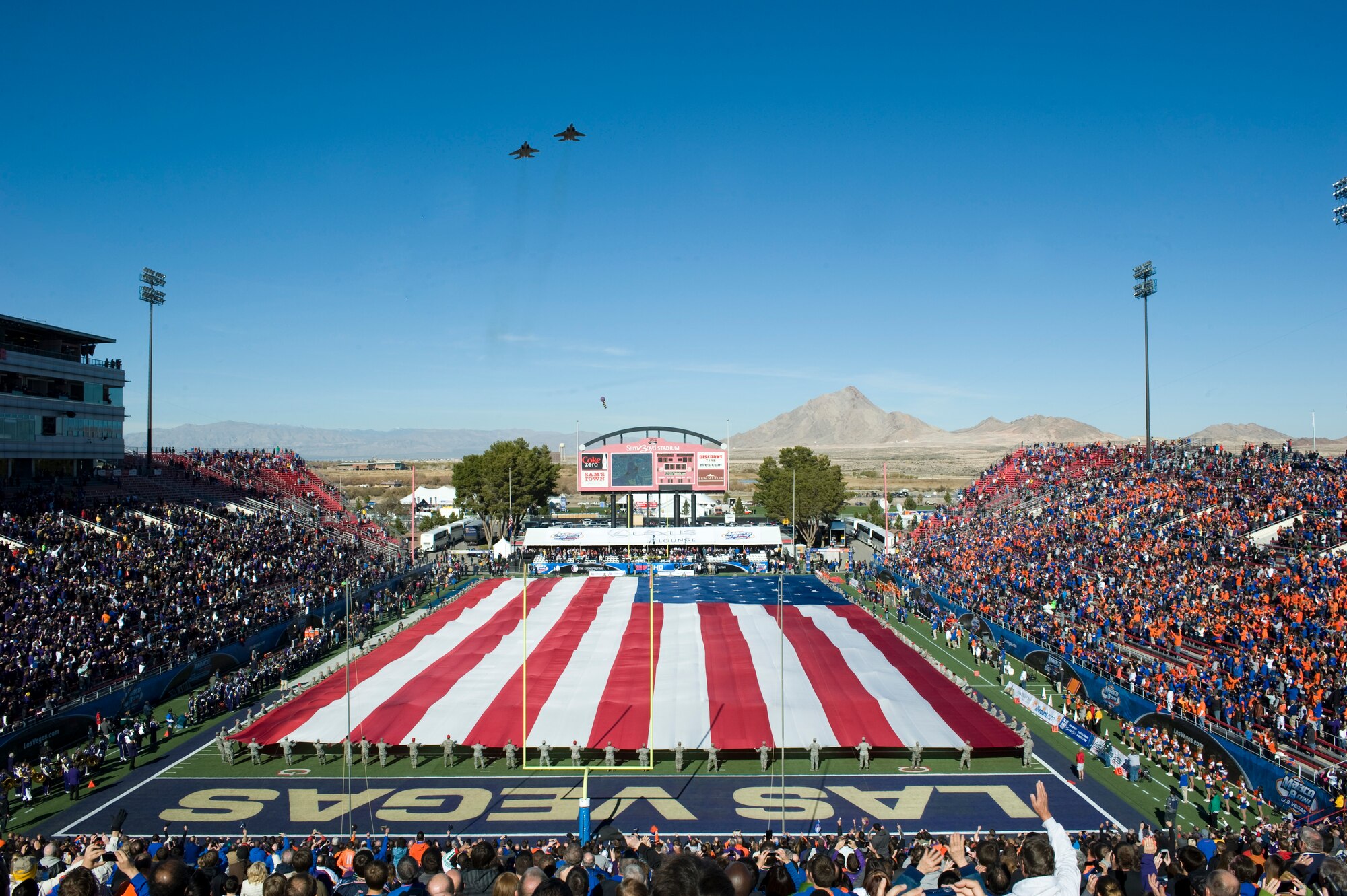 Nellis and Creech Airmen hold a 100 yard long American flag while two F-15 Eagles from Nellis Air Force Base fly over during the opening ceremony at the Maaco Bowl Dec. 22, 2012, in Las Vegas. This year's Maaco Bowl game was between University of Washington and Boise State University. (U.S. Air Force photo by Airman 1st Class Christopher Tam)
