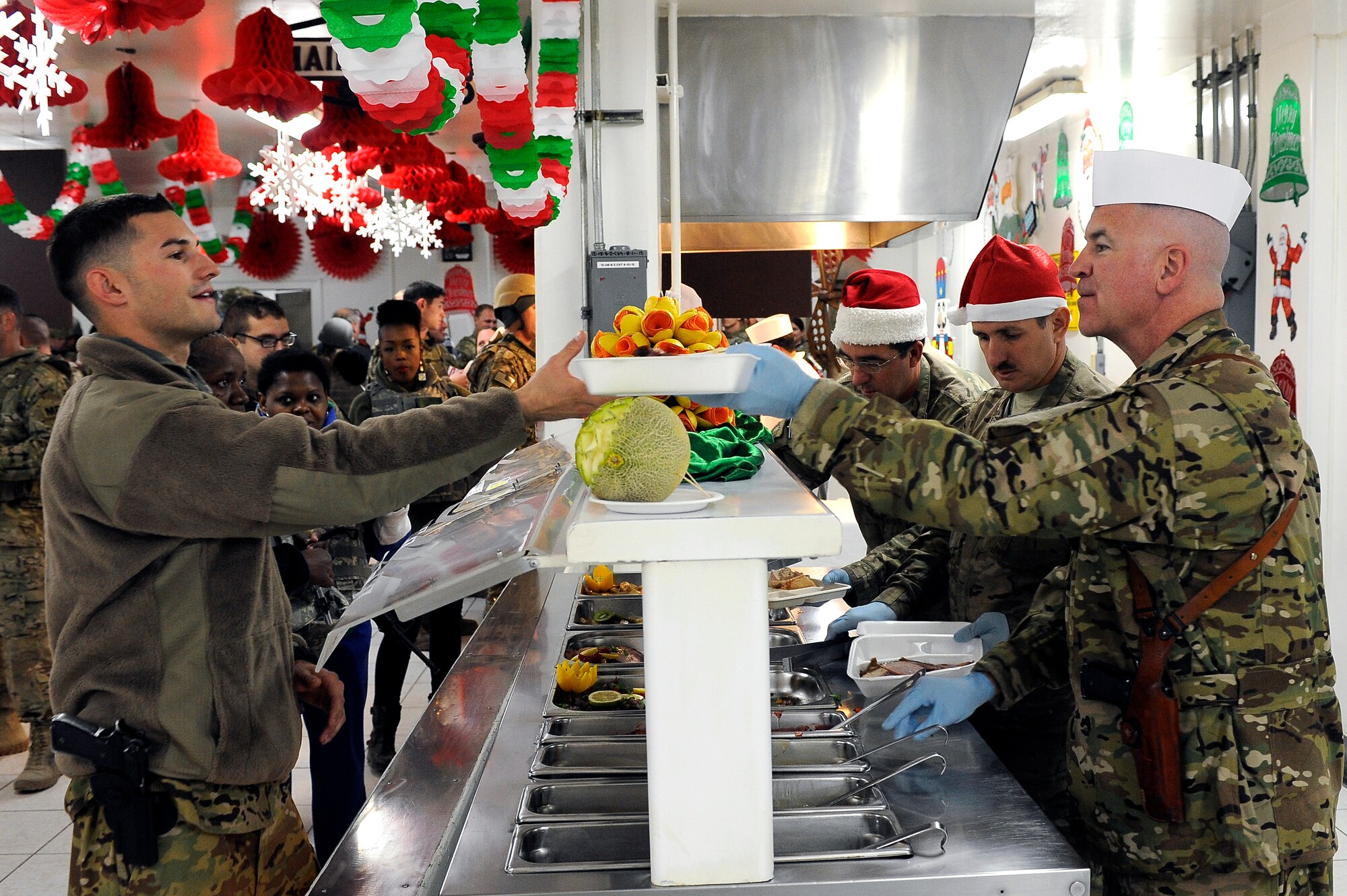 Col. Timothy Hogan, 455th Air Expeditionary Wing vice commander, Chief Master Sgt. Lawrence Bucher, 455th Expeditionary Aircraft Maintenance Squadron, and 455th AEW Command Chief Master Sgt. Steven Bohannon, serve Airmen turkey and other dishes during a Christmas Day celebration at Bragram Airfield, Afghanistan, Dec. 25, 2012. Squadron and wing leadership served meals throughout the holidays to boost the morale of the servicemen and women. (U.S. Air Force photo/Senior Airman Chris Willis)