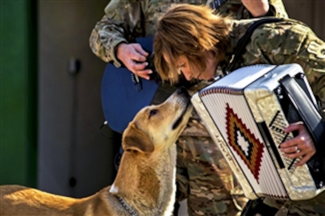 U.S. Air Force Senior Airman Michelle Hooper interacts with Badger during a performance for the 438th Medical Detachment veterinary service on Kandahar Airfield, Afghanistan, Dec. 19, 2012. Hooper, a musician, is assigned to "Total Force," the U.S. Air Forces Central Band, which played at several work centers on the base.