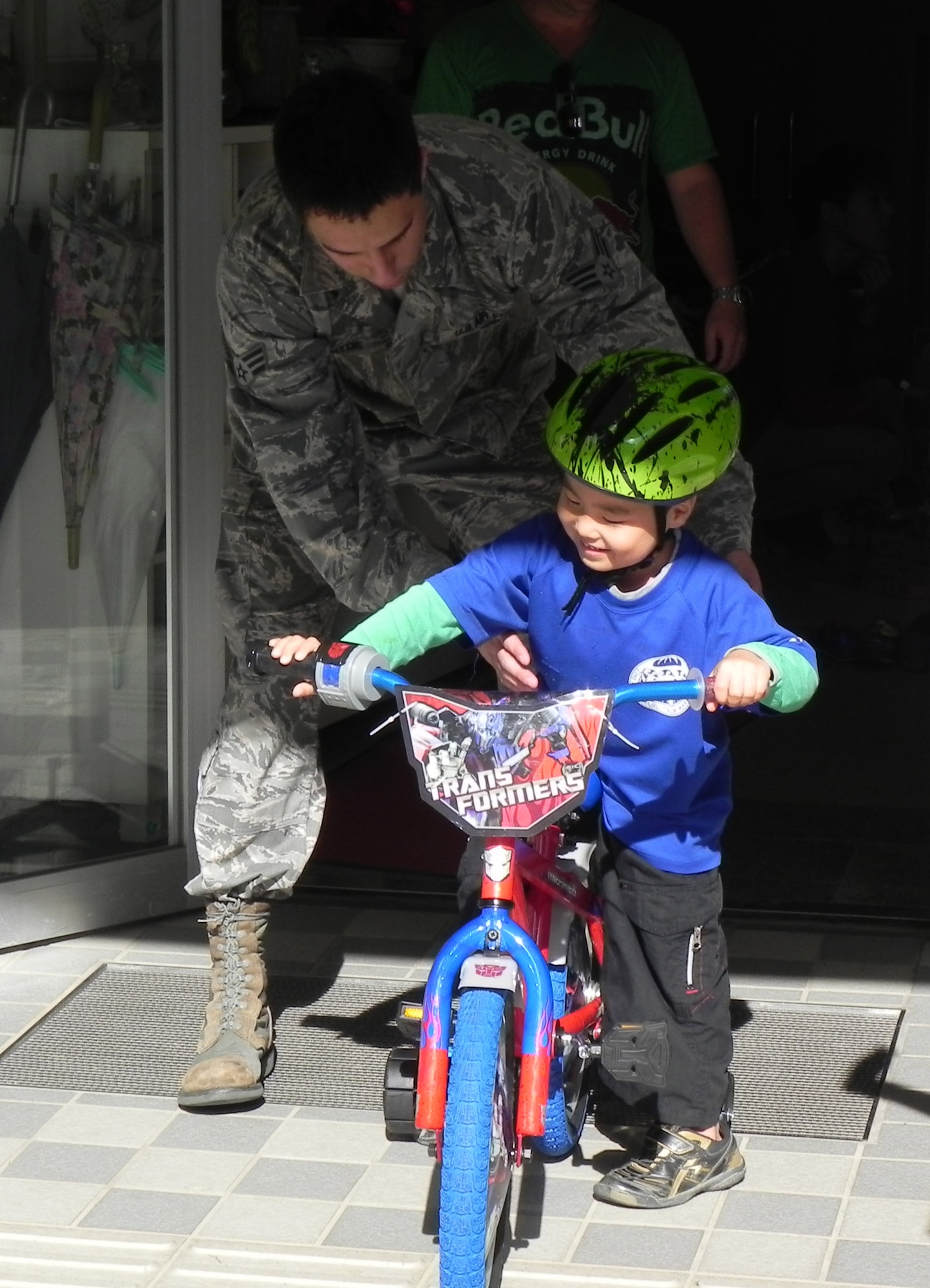 U.S. Air Force Senior Airman Cody Hyde, 18th Dental Squadron dental assistant, helps a child get on his bike at the Ai Rin Orphanage in Okinawa, Japan, Dec. 21, 2012. The 18th Medical Group collected more than 40 toys for different age groups to give Christmas presents to the children at the orphanage. (U.S. Air Force photo/Capt. Jan Kolenda)  