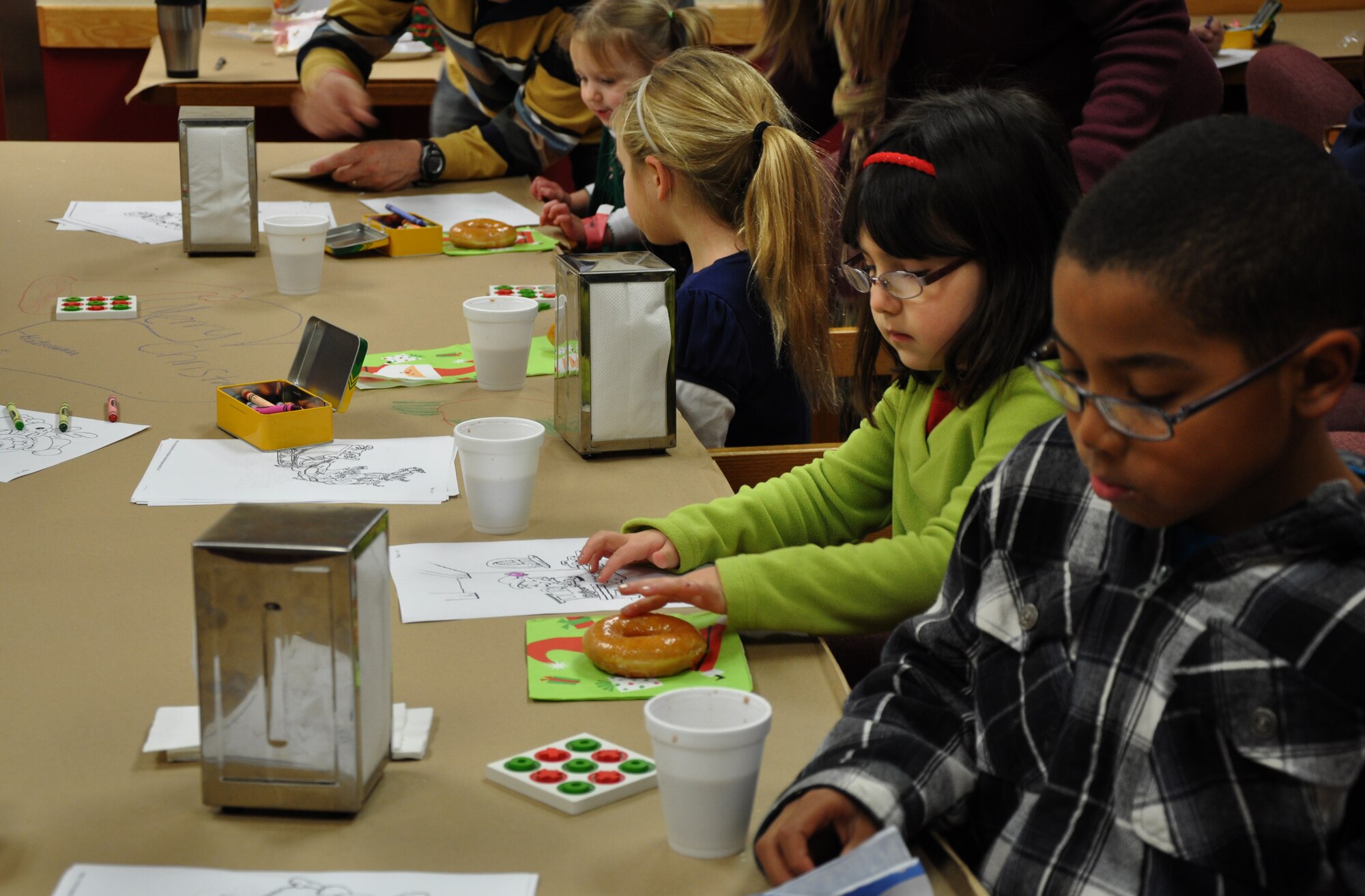 Children and families enjoy hot chocolate and donuts while coloring and playing tic-tac-toe at the 7th Space Warning Squadron NORAD Santa Tracking event on Christmas Eve. This event occurs every year at Beale Air Force Base to create a family atmosphere primarily for children with deployed parents. (U.S. Air Force photo by 2nd Lt. Siobhan G. Bennett/Released)