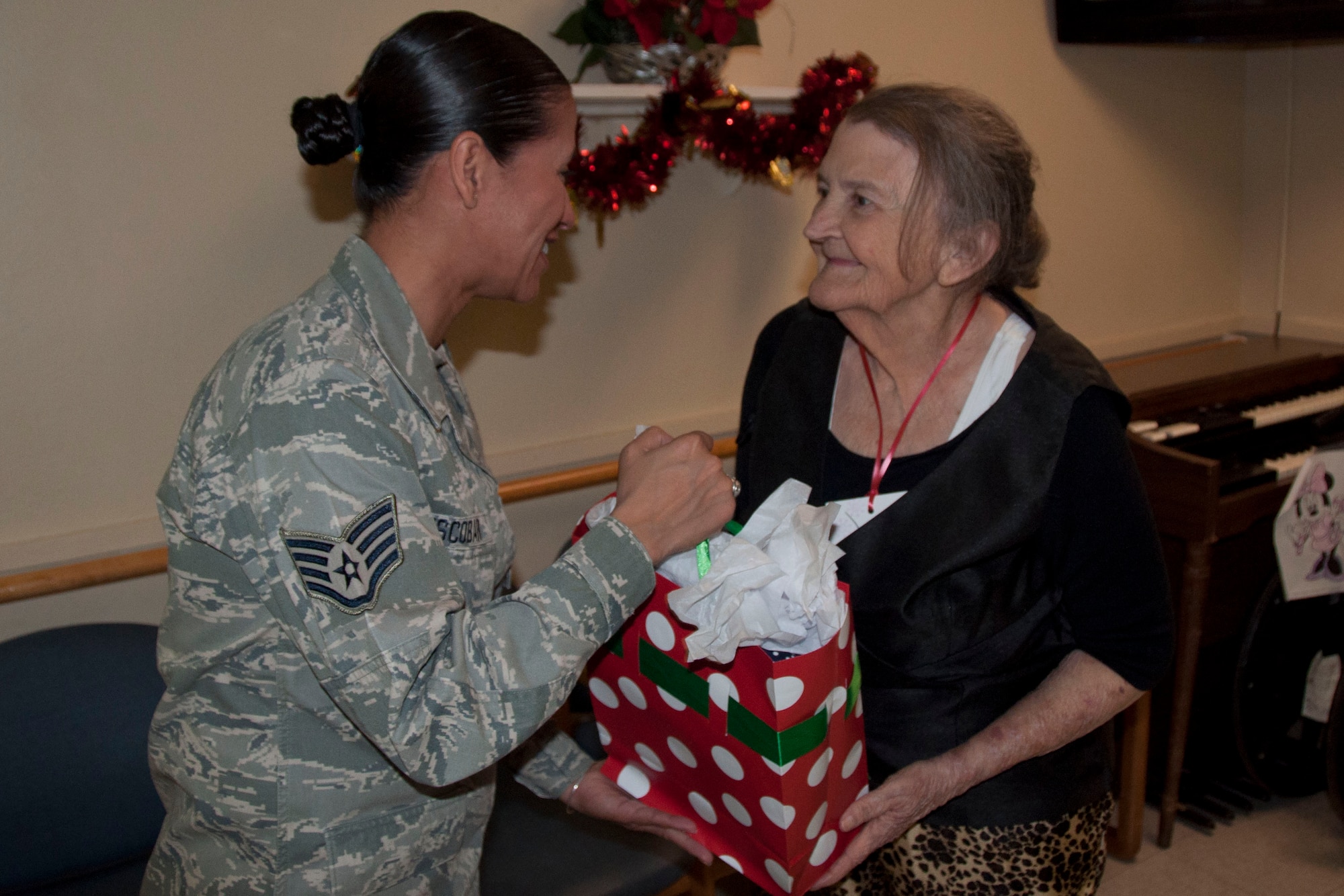 Staff Sgt. Maria Escobar, a Military Training Instructor  with the 324th Training Squadron helped pass out gifts durng Operation Grayson Square. Military Training Instructors and other members of the 737th Training Group played Santa at a local skilled nursing facility delivering gifts to 84 residents this season. The 737th Training Group has been "elfing it up" with Operation Grayson Square since 1999. (U.S. Air Force Photo/Melinda Mueller) 

