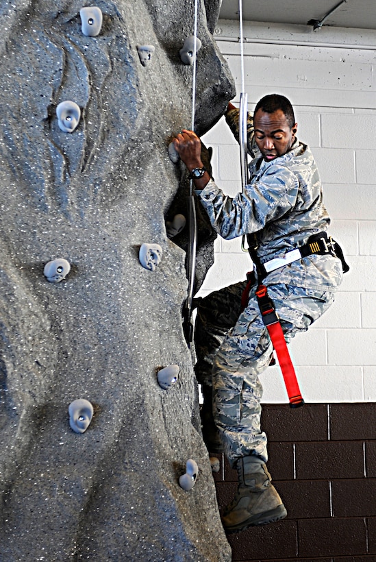Lt. Col. Anthony Mims, 28th Logistics Readiness Squadron commander, scales the new rock wall after the Pride Hangar fitness area and rock wall ribbon-cutting ceremony at Ellsworth Air Force Base, S.D., Dec. 19, 2012. The climbing wall will soon be an option for organized physical training sessions, and will be available for Airmen, family members and retirees not participating in an organized PT session with a reservation and at a nominal fee. (U.S. Air Force photo by Airman Ashley J. Woolridge/Released) 