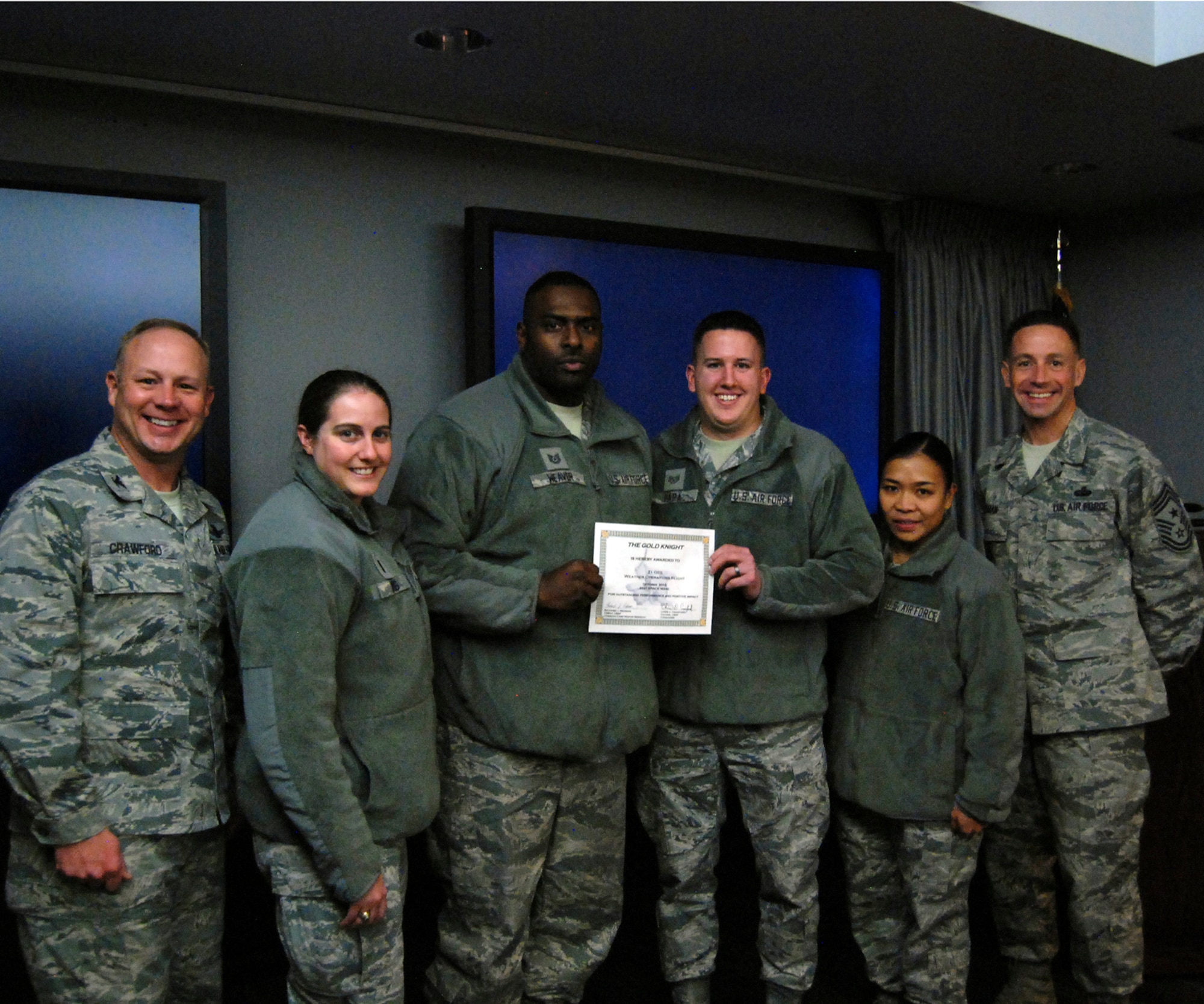 Col. Chris Crawford (left), 21st Space Wing commander, and Chief Master Sgt. Richard Redman (right), 21st SW command chief, award the 21st Operations Support Squadron the October Gold Knight award. (U.S. Air Force photo/Senior Airman Jacob Morgan)