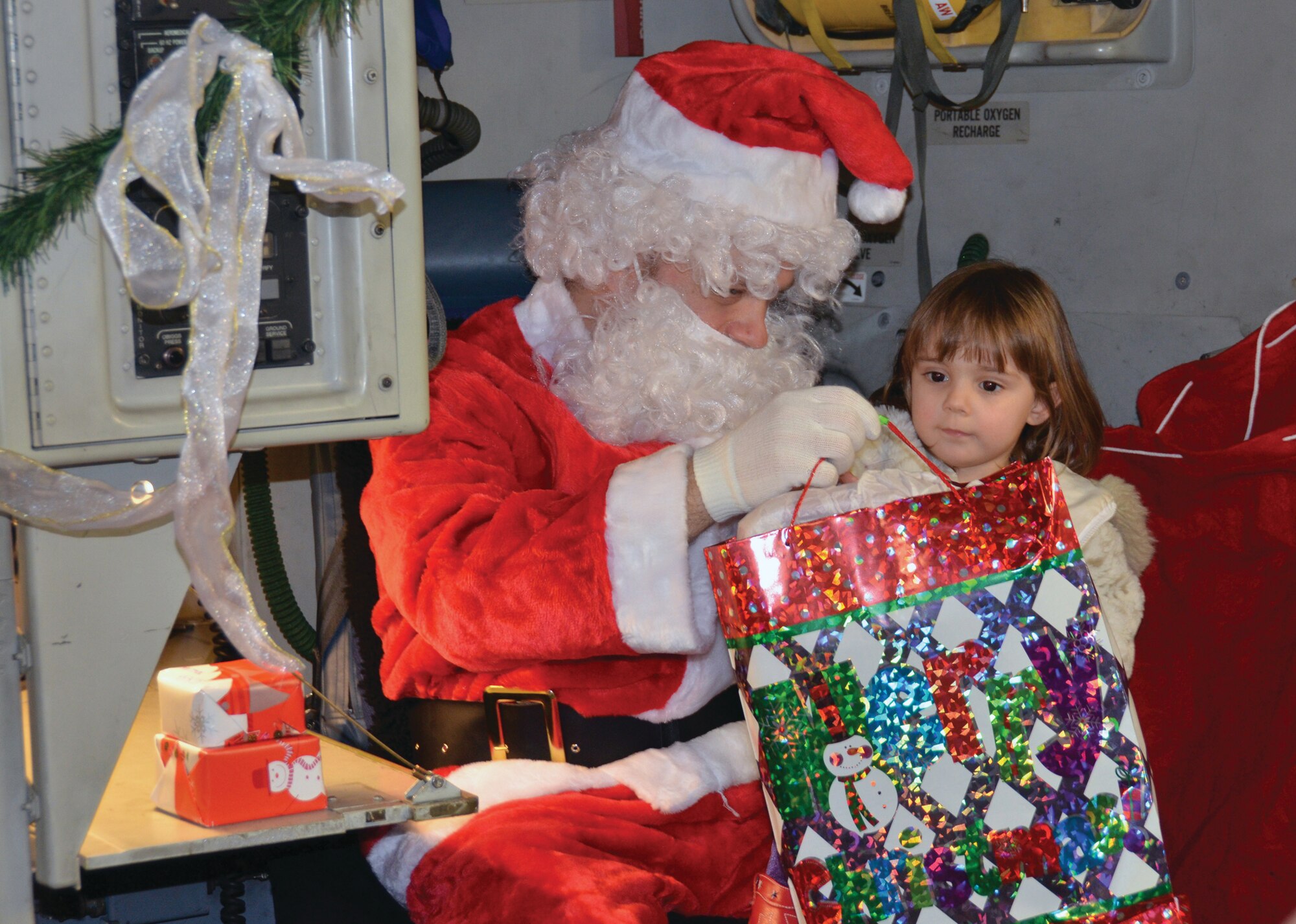 WRIGHT-PATTERSON AIR FORCE BASE, Ohio - Capt. John “Santa Claus” Ludtke, 445th Aerospace Medicine Squadron flight surgeon, delivers gifts to children of 445th Airlift Wing members during the Dec. 16 unit training assembly. A C-17 Globemaster III decked out in holiday décor acted as Santa’s sleigh during his visit with more than 130 family members. (U.S. Air Force photo/Master Sgt. Charlie Miller)
