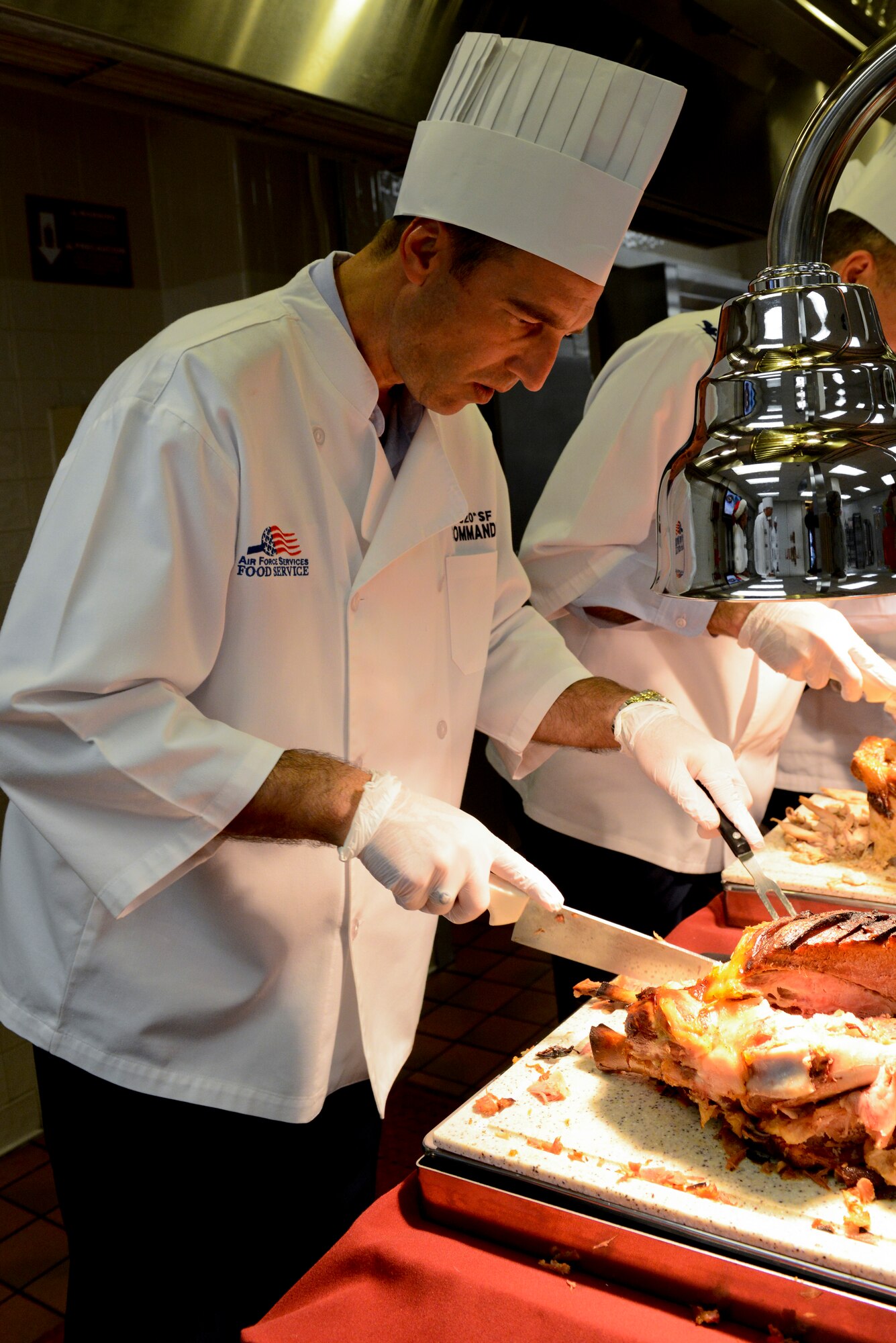 U.S. Air Force Col. Paul Kasuda, 820th Base Defense Group commander, carves ham during Christmas lunch service at the Georgia Pines Dining Facility on Moody Air Force Base, Ga., Dec. 25, 2012. The lunch service was open to all active duty Airmen, their families and retirees in the local area.  (U.S. Air Force photo by Staff Sgt. Joshua J. Garcia/Released) 