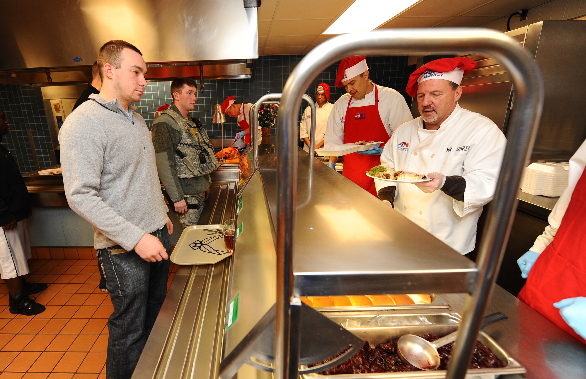 U.S. Air Force Airman 1st Class Michael Giles, 55th Strategic Communications Squadron, selects items from the buffet with Tom Fahrer, 55th Force Support Squadron deputy commander, working side by side with wing leadership to ensure the Airmen have Christmas dinner at the Ronald L. King Dining Facility, Dec. 25, Offutt Air Force Base, Neb.  (U.S. Air Force Photo by Josh Plueger/Released)