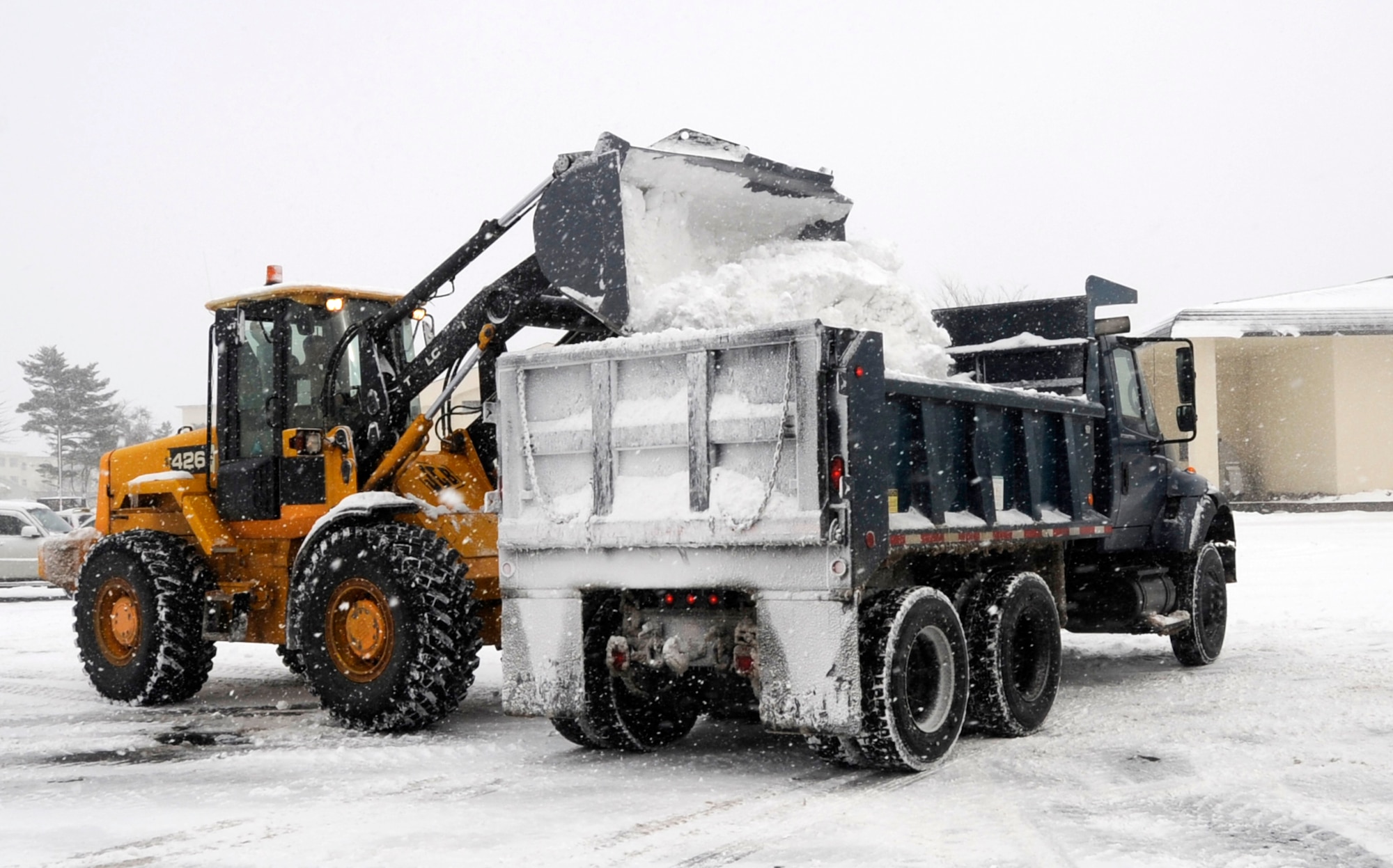 Members of the 35th Civil Engineer Squadron snow removal team, work together to clear the base club parking lot Dec. 27, 2012, at Misawa Air Base, Japan. After priority roadways are finished, 35 CES clear secondary roads and large parking lots daily if snowfall continues. (U.S. Air Force photo by Airman 1st Class Kaleb Snay)