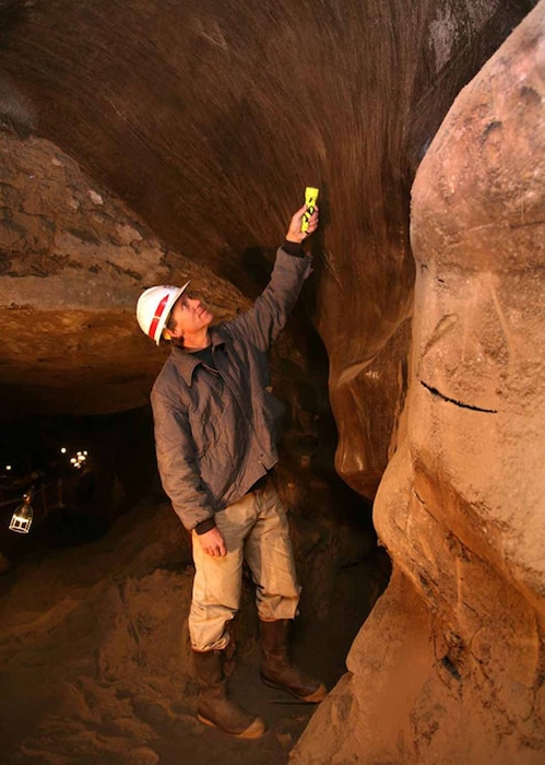 A CRREL researcher studies an ice wedge, one of numerous massive ice features in the tunnel.