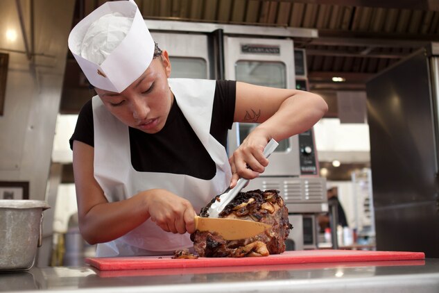 MARINE CORPS BASE HAWAII - Cpl. Blanquivett Robinson, 2012 Chef of the Year winner, and a food service administration clerk, Anderson Hall Dining Facility, carves a pork roast in preparation for the upcoming competition at the dining facility, Dec. 19. (Official U.S. Marine Corps photo by Cpl. Vanessa American Horse)