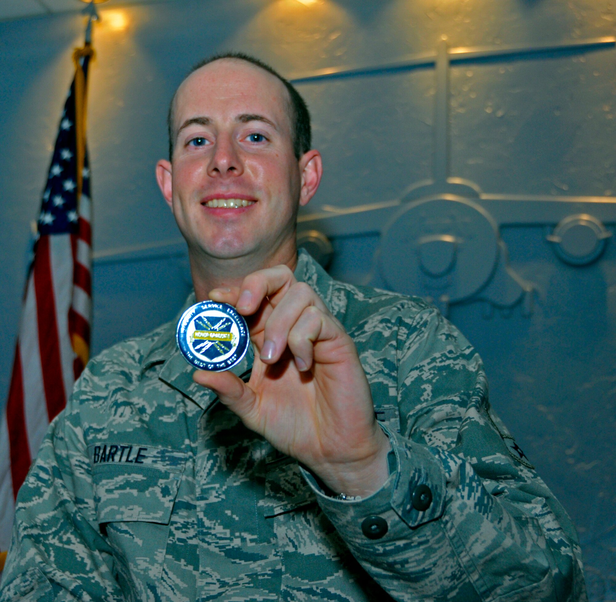 Airman 1st Class Glenn Bartle, 728th Airlift Squadron, holds his Basic Military Training Honor Graduate coin at the 446th Airlift Wing's Headquarters on McChord Field, Wash., Dec. 28. Bartle earned the coin by performing at such a high level during BMT at Joint Base San Antonio, Texas, that his scores placed him in the top 10 percent of the almost 800 Airmen he graduated with. He completed the training Dec. 7. "I was just a bit more focused throughout the entire process of BMT. I studied when I was supposed to study and listened when I was supposed to listen. I paid attention to what was being said as opposed to how the Training Instructors were saying it," said Bartle. He leaves for technical school back at Joint Base San Antonio in January to begin the training to become a Aircraft Loadmaster . (U.S. Air Force Photo/Staff Sgt. Rachael Garneau)