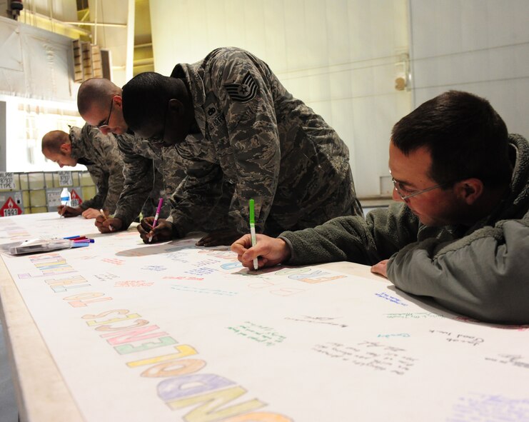 Members of team Dyess sign a banner in support for the community of Sandy Hook, Conn. Dec 28, 2012. Team Dyess Airmen, employees and family members had an opportunity to tour a B-1 aircraft and sign the banner for those affected by the recent tragedy. (U.S. Air Force photo by Senior Airman Chelsea Browning/Released)