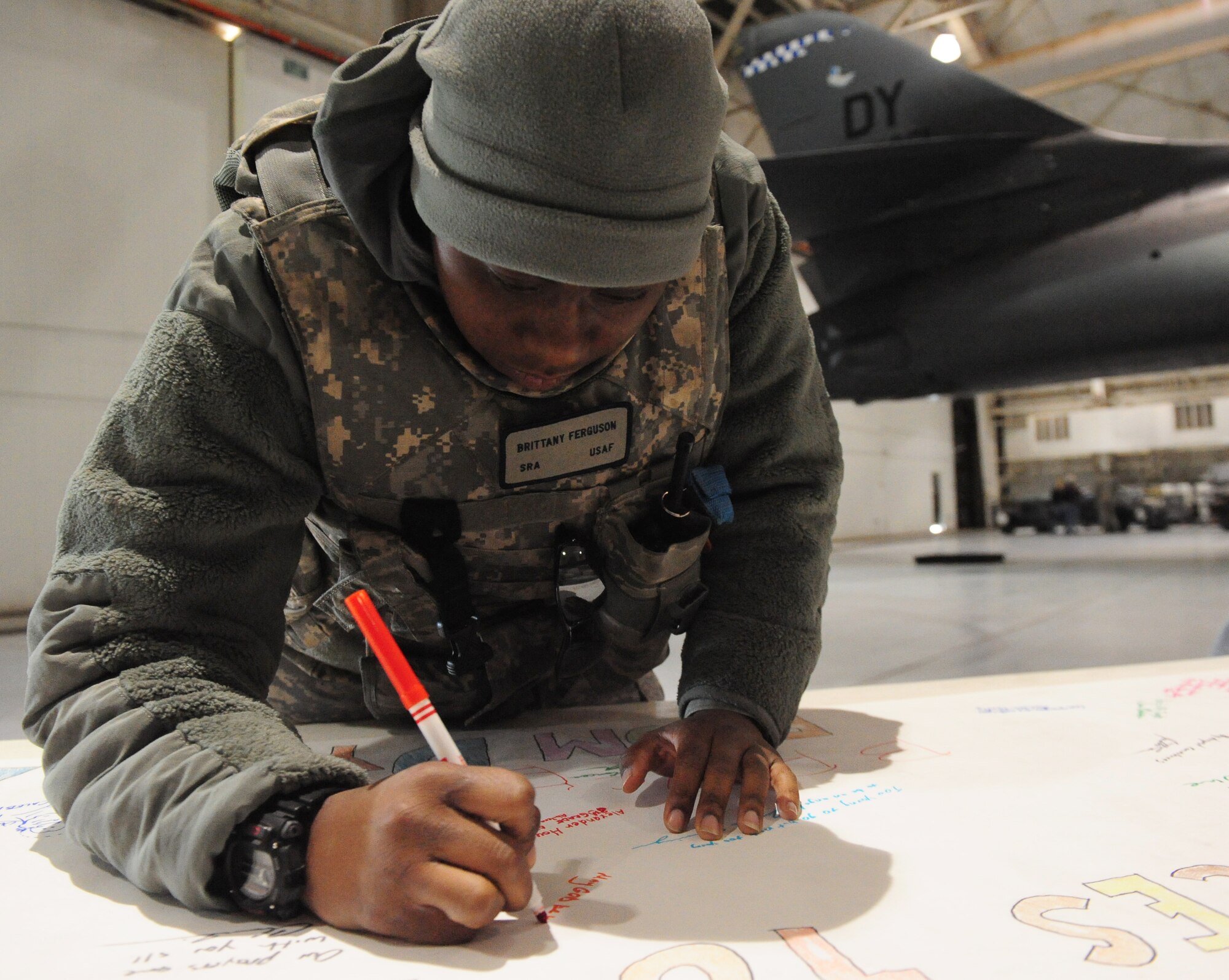 Senior Airman Brittany Ferguson, 7th Security Forces Squadron, signs a banner in support for the community of Sandy Hook, Conn. Dec 28, 2012. Team Dyess Airmen, employees and family members had an opportunity to tour a B-1 aircraft and sign the banner for those affected by the recent tragedy. (U.S. Air Force photo by Senior Airman Chelsea Browning/Released)
