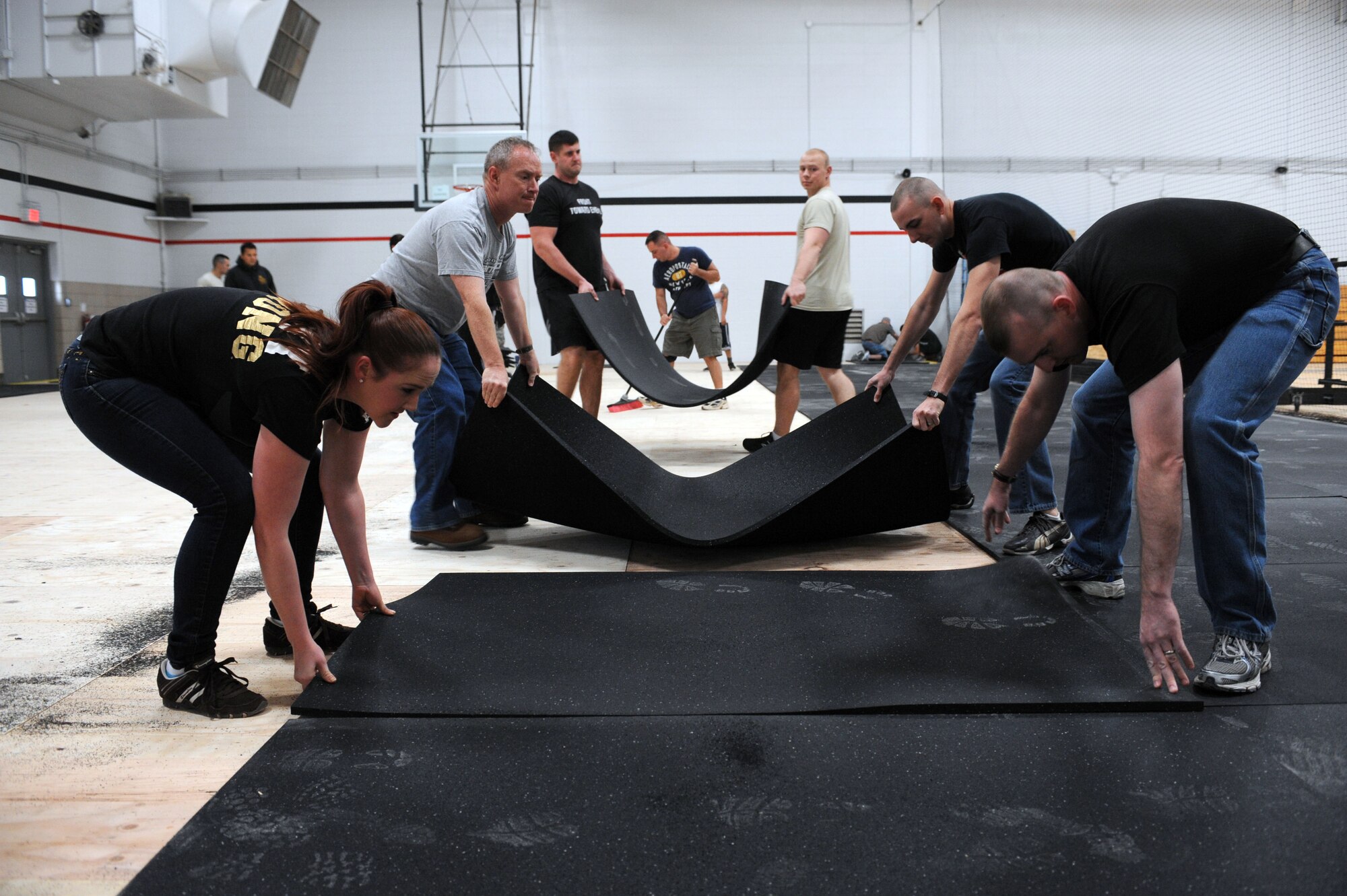 U.S. Air Force Airmen and U.S. Army Soldiers lay mats on the floor in the new cross function fitness area at the Haeffner Fitness Center on Davis-Monthan Air Force Base, Ariz., Dec. 27, 2012. The Airmen and Soldiers volunteered to put the mats in place in response to a request for help from U.S. Air Force Maj. Gregory Stack, 355th Fighter Wing executive officer. (U.S. Air Force photo by Senior Airman Timothy Moore/Released)