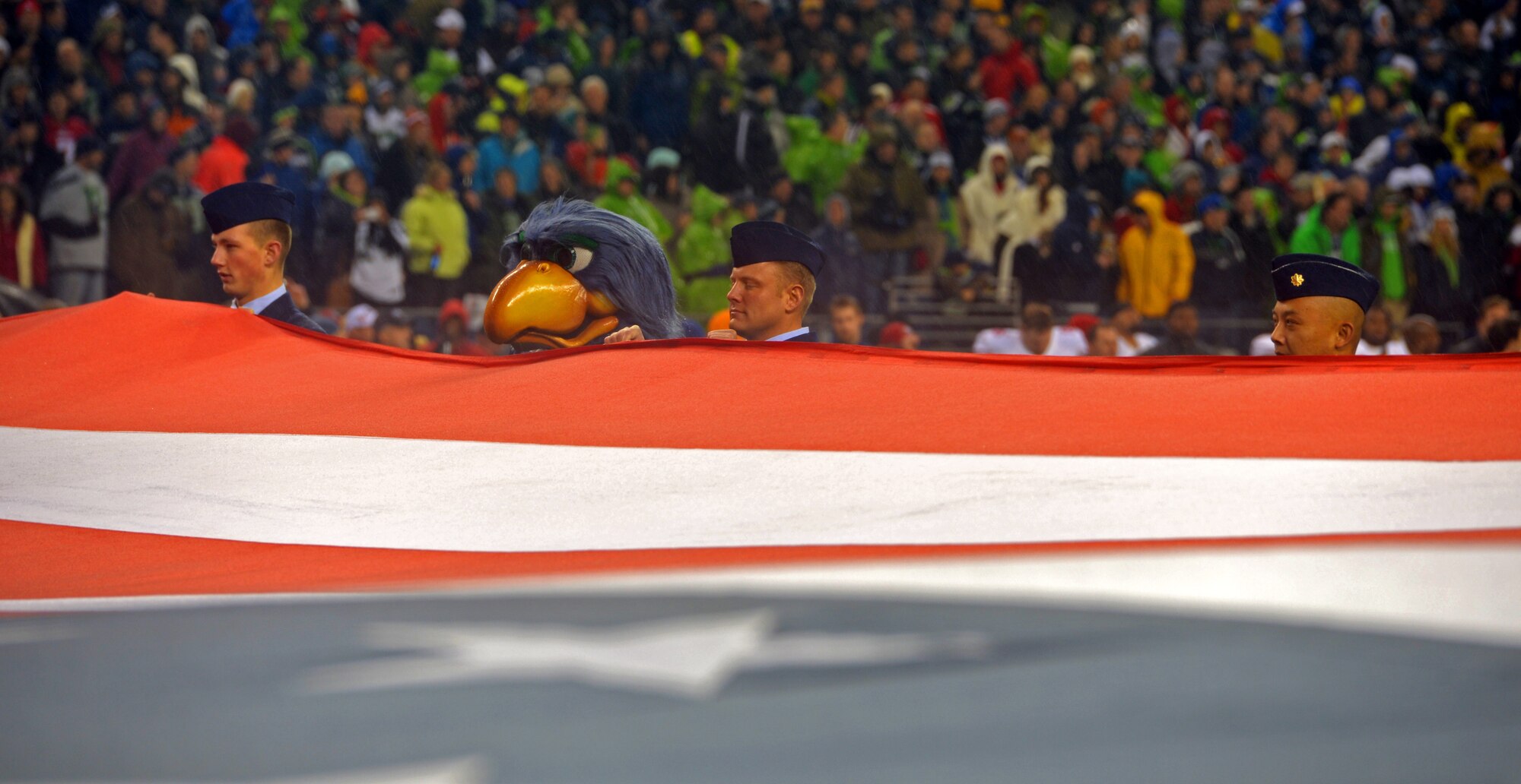 Airman 1st Class Cody Hoef (left), 446th Civil Engineer Squadron, Blitz, the Seattle Seahawk's mascot, Tech. Sgt. Kurt Lewandowski (middle), 62nd Airlift Wing, and Maj. Bakhtiar Pribadi, 446th Aerospace Medical Squadron, hold the American flag during the pre-game ceremony for the Seahawks- San Francisco 49ers game Dec. 23 in Seattle, Wash. The 446th Airlift Wing, headquartered at McChord Field, had 21 Reservists on the field. (U.S. Air Force Photo/Master Sgt. Todd Wivell)