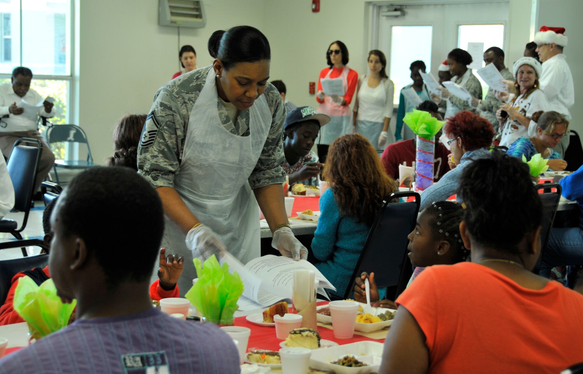 Senior Master Sgt. Wanda Symons, 482nd Force Support Squadron military personnel programs chief, helps read the lyrics of Christmas carols during a Christmas meal at the Chapman Partnership in Homestead, Fla., Dec. 25. Several members of Homestead Air Reserve Base, Fla., organized by the base's Unit Advisory Council, volunteered to help the Chapman Partnership, a local organization which provides comprehensive services to the homeless, during their Christmas meal. Homestead ARB has also participated with Chapman Partnership on other events such as food drives and holiday events.  (U.S. Air Force photo/Senior Airman Jaimi Upthegrove) 
