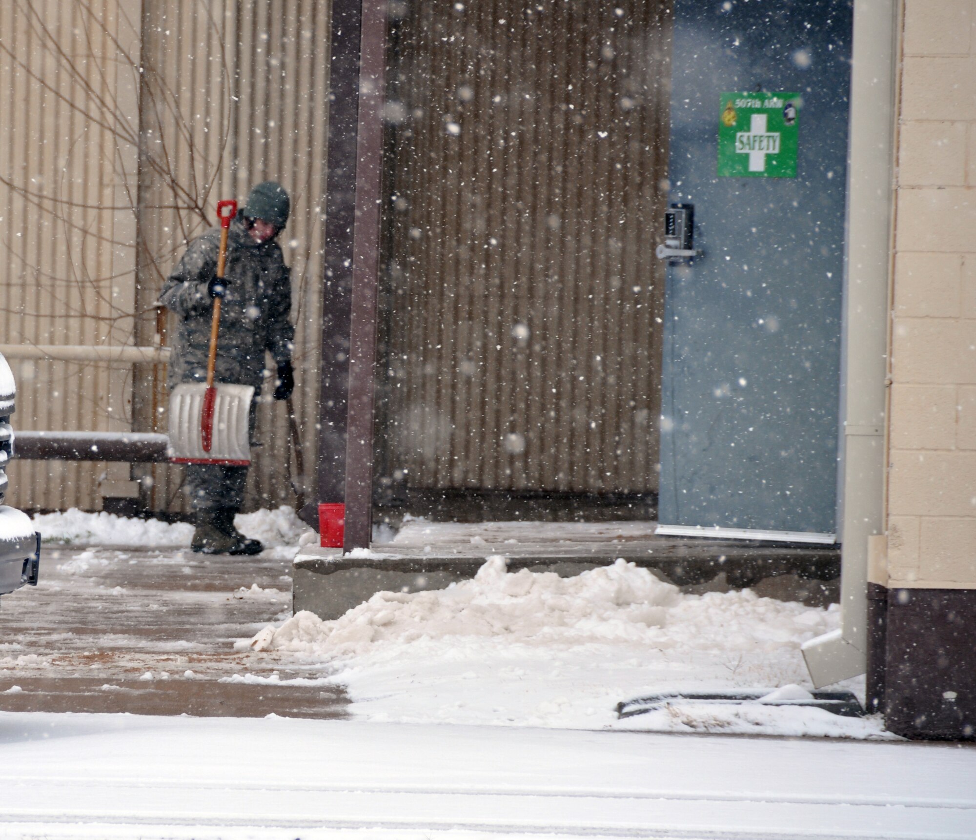 Always vigilant!  Tech. Sgt. Regina Rector, 507 Air Refueling Wing Ground Safety Manager braves the frigid temperatures and whiteout conditions to shovel a sidewalk and lay down some sand in an entry way.  Rector spent a good deal of her morning checking sidewalks and entry ways around the wing ensuring they are safe for members to get in and out of buildings.  (Photo by Senior Airman Mark Hybers)