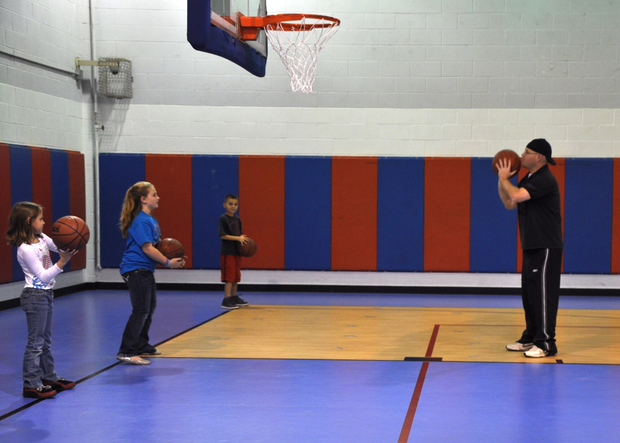 GOODFELLOW AIR FORCE BASE, Texas – (right) Brian Stansbury, Youth Center basketball coach, teaches a group of children the proper way to shoot a basketball during the Youth Basketball Camp at the Youth Center here Dec. 26. During the Youth Basketball Camp the children learned about passing, dribbling, shooting, rebounding and basic defense. (U.S. Air Force photo/ Airman 1st Class Joshua Edwards)