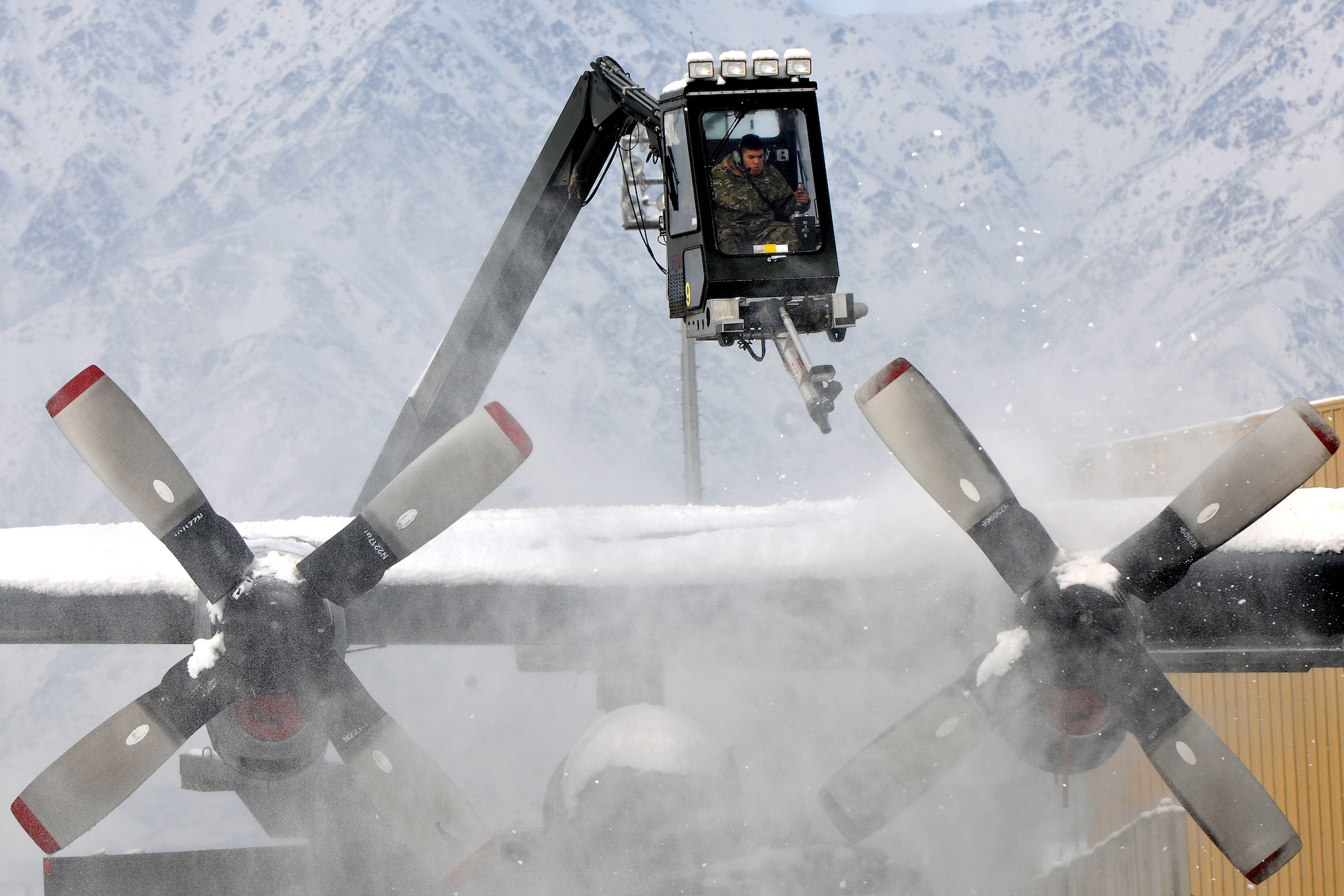 Members of the 455th Expeditionary Maintenance Squadron de-ice a C-130 Hercules at Bagram Air Field, Afghanistan, Dec. 28, 2012.  Maintenance Airmen removed snow from the aircraft to minimize the possibility of damage prior to taxi and take off. (U.S. Air Force photo/Senior Airman Chris Willis)