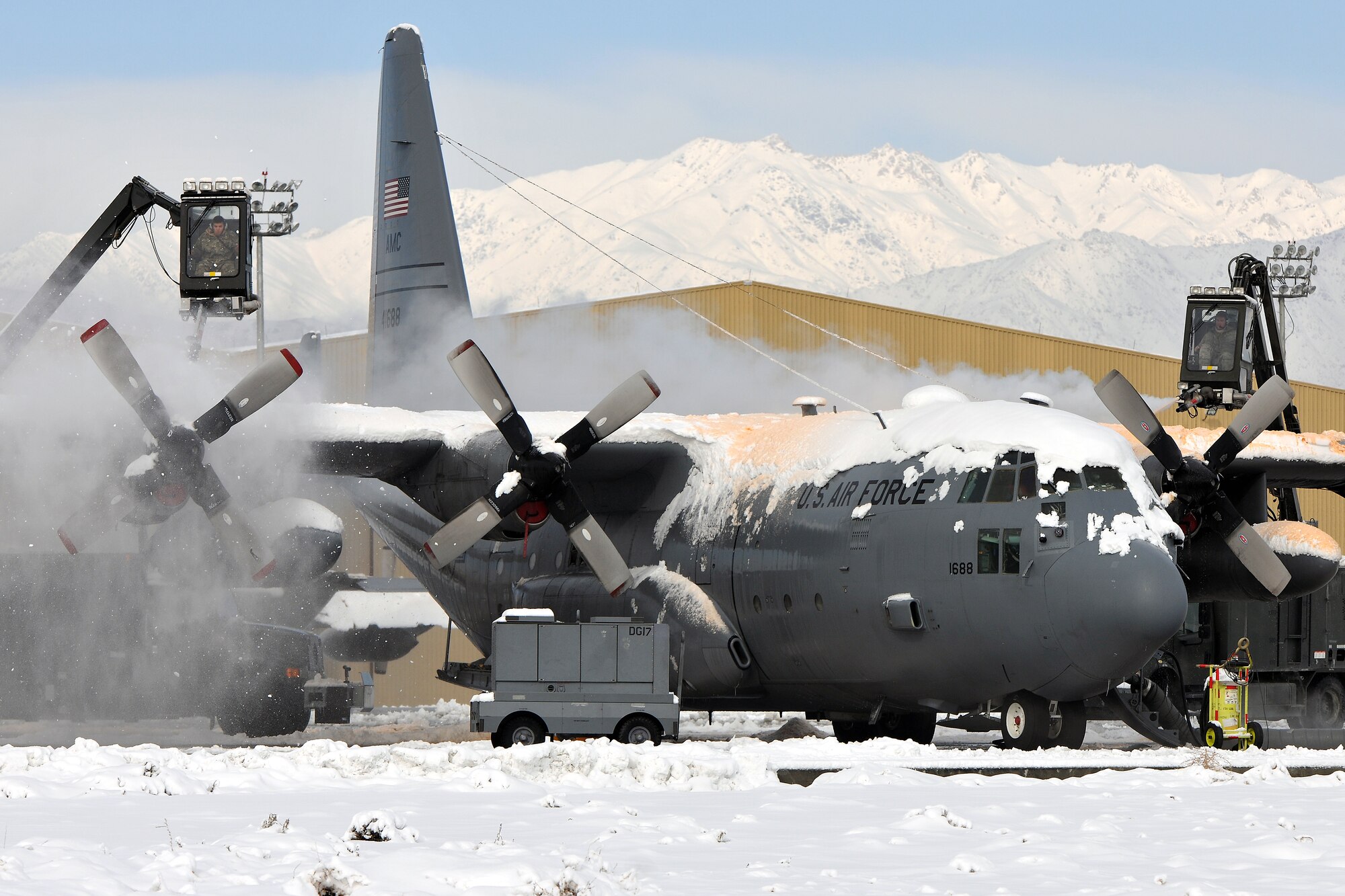 Members of the 455th Expeditionary Maintenance Squadron de-ice a C-130 Hercules at Bagram Air Field, Afghanistan, Dec. 28, 2012.  Maintenance Airmen removed snow from the aircraft to minimize the possibility of damage prior to taxi and take off. (U.S. Air Force photo/Senior Airman Chris Willis)