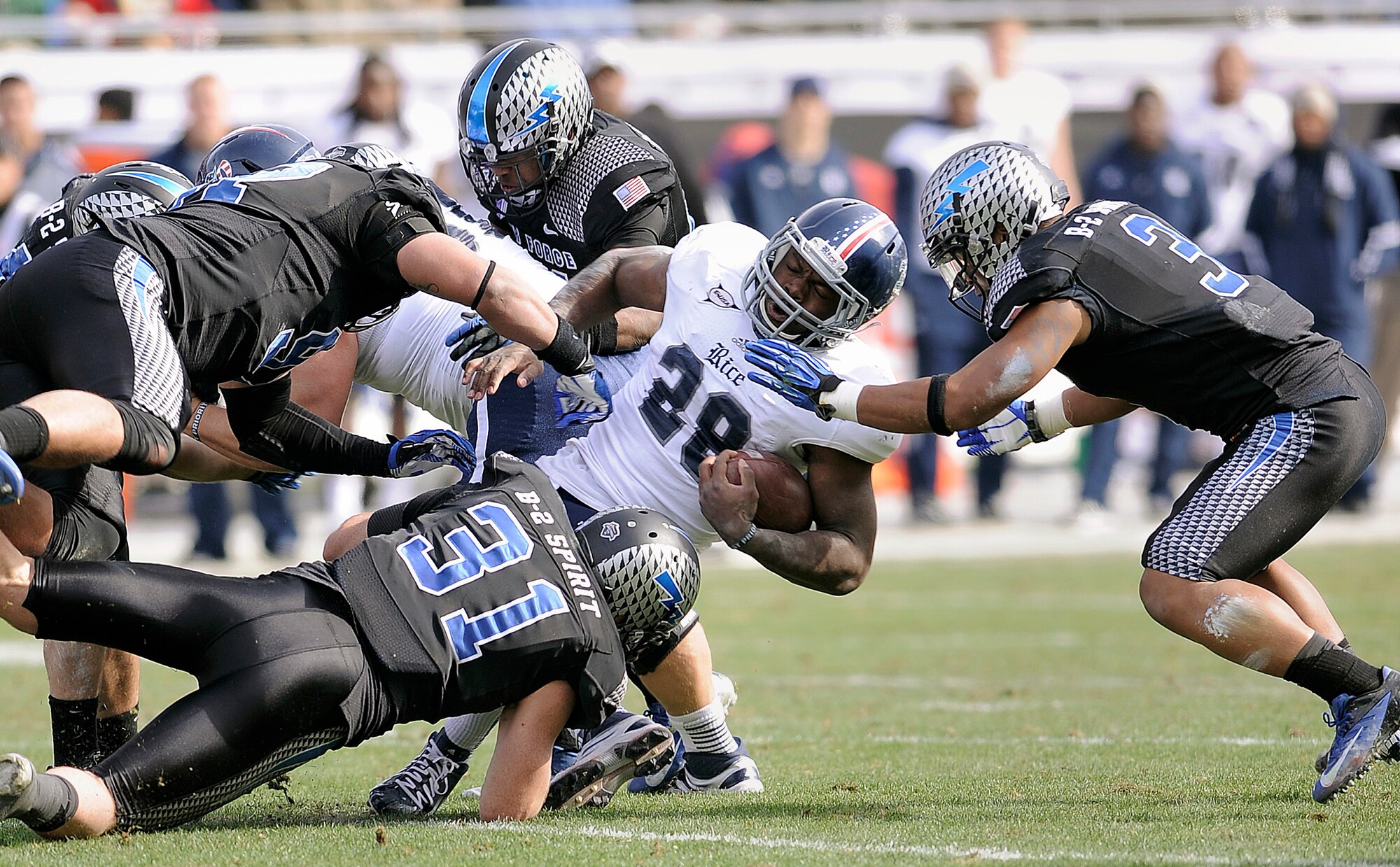 Rice running back Charles Ross is dragged down by a host of falcon defenders, including defensive backs Brian Lindsay (bottom) and Chris Miller (right), during the Armed Forces Bowl in Fort Worth, Texas, Dec. 29, 2012. Though the Falcons made school history with their sixth-straight bowl game appearance, they fell to the Owls, 33-14. (U.S. Air Force photo/Sarah Chambers)