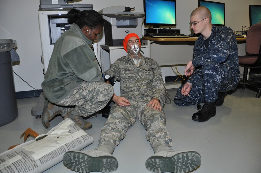 NIAGARA FALLS AIR RESERVE STATION N.Y. - Staff Sgt. Marcdala Semexan (left), 914th Aeromedical Staging Squadron medical technician, and HM 3rd Class William Gunnersen (right), Operational Health Support Unit Detachment H, attend to simulated hunting accident patient Tech. Sgt. Jeremy Hayes, 914 ASTS, during a joint Air Force and Navy medical training exercise here December 2, 2012.  (U.S. Air Force photo by Master Sgt. Kevin Nichols)