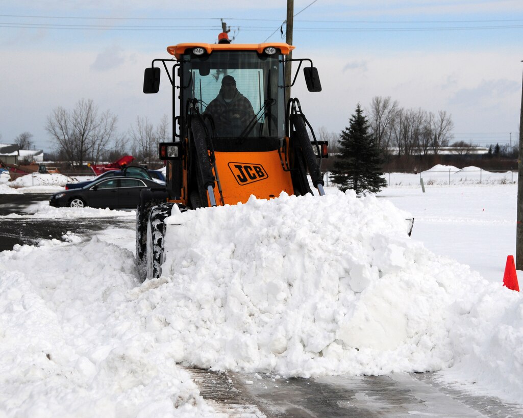 Dan Wood, heavy equipment operator for Satellite Services Incorporated clears a parking lot of fresh fallen snow for the last time this year at the Niagara Falls Air Reserve Station, N.Y. on December 31,2012 New Year's Eve. The snow is cleared by a unique method called "Slot Dozing". The plow operator creates a "slot" in the snow which keeps the snow from falling off the sides of the plow. The plow will make several passes with additional snow into the slot thus allowing more volume to be removed than the traditional method. (U.S. Air Force photo by Peter Borys)