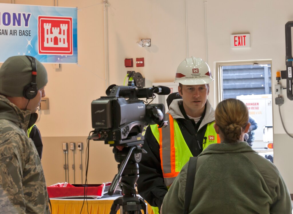 Andrew Rajala, resident engineer at the Far East District’s Kunsan Resident Office, is interviewed by the American Forces Network about Kunsan Air Base's new aircraft maintenance facility Dec. 18. The project consolidates 18 shops spread around the base into three main shops.  With all three now housed in one maintenance facility close to the flight line, the response time to urgent aircraft maintenance issues is greatly reduced.  The accessory shop will provide one location for aircraft components such as wheels, tires, external tanks, and hydraulic and electrical systems to be repaired or replaced.  The complex’s fabrication and armament shops were completed in 2011. The previously-completed fabrication shop includes sections for structural sheet metal, aircraft metals technology, non-destructive inspections, and survival equipment.  It also includes a state-of-the-art paint booth and sanding room.  The armament shop provides space for gun maintenance and a mission equipment storage area.  It also features administration offices, a classroom, and training room.

