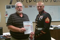 Mankato, Minn., recruiter Sgt. Derrick T. Fladseth presents Waterville Elysian Morristown High School head football coach Jon Bakken with a free pass to the Glazier Clinic in Minneapolis Feb. 17-19.