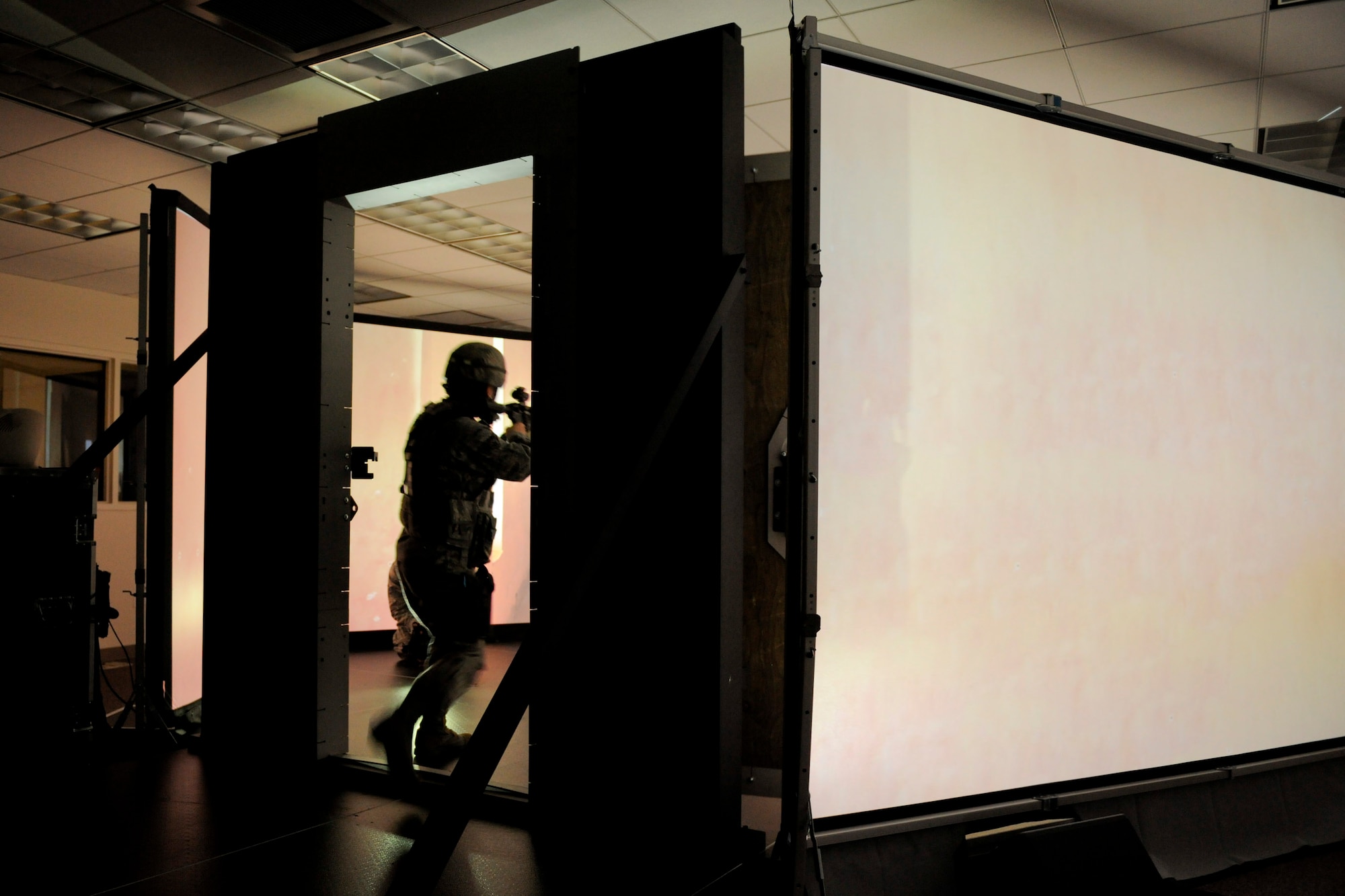 VANDENBERG AIR FORCE BASE, Calif. -- Members from the 30th Security Forces Squadron storm a virtually simulated room in a firearms training simulator at the Combat Arms Training Complex (Building 21308) here Friday, Jan. 27, 2012. The new simulator provides a virtual training environment for Vandenberg members to practice real-world combat tactics and scenarios based on Air Force qualification courses. (U.S. Air Force/Staff Sgt. Levi Riendeau)
