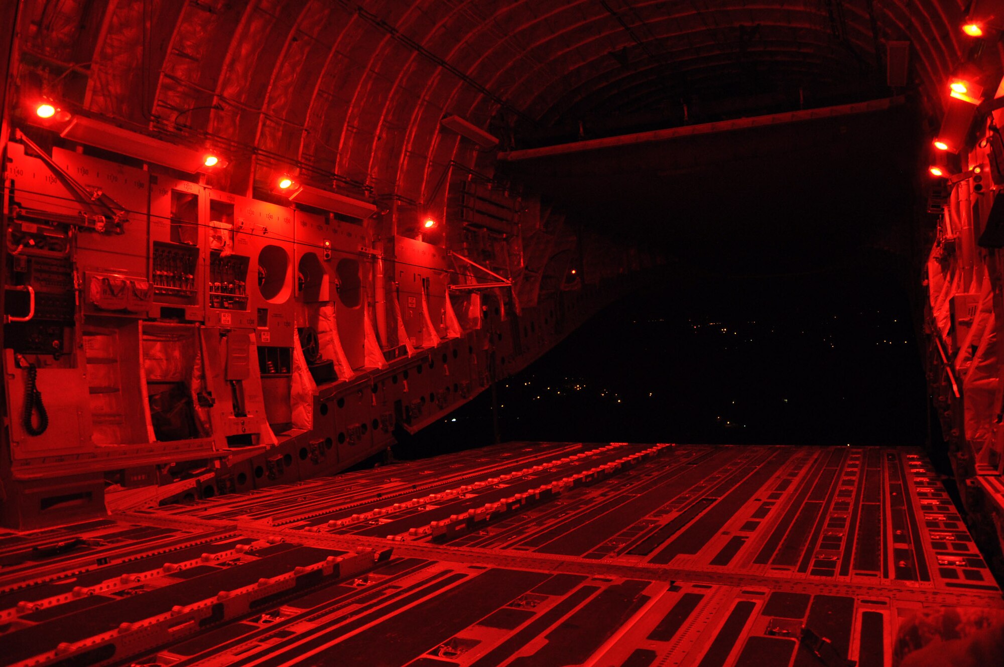 The rear door of a C-17 Globemaster III aircraft lays open, exposing the night sky and dimly lit ground below, during a night airdrop mission January 31, 2012. (U.S. Air Force photo by 1st Lt. Joseph Simms)