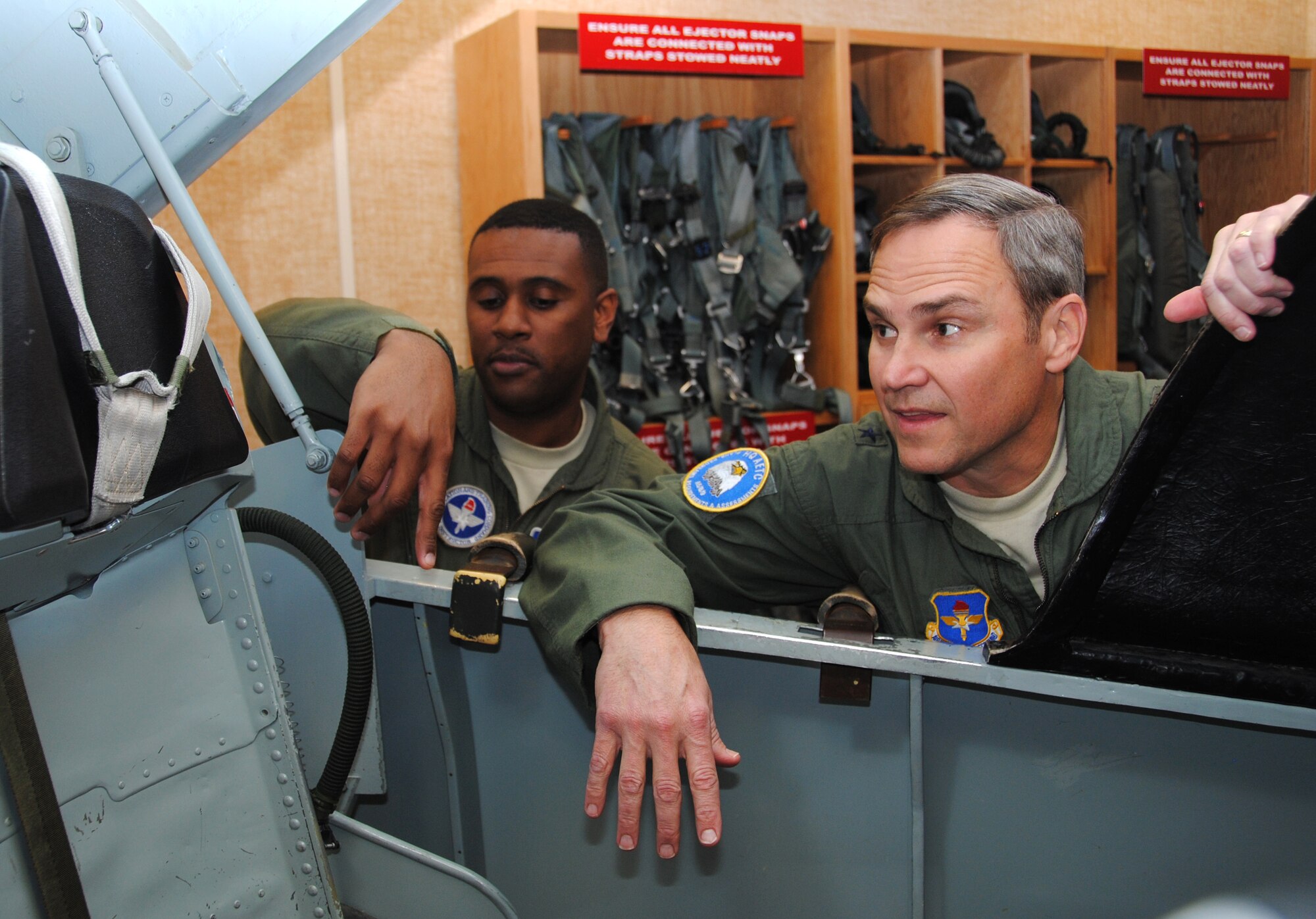 Tech. Sgt. Iyendo Manchester, left, gives Brig. Gen. Chris Nowland a refresher on getting out of the T-38 Talon cockpit during an emergency. General Nowland, the director of Plans, Programs, Requirements and Assessments at Headquarters, Air Education and Training Command at Randolph Air Force Base, Texas, and a former commander of the 71st Flying Training Wing at Vance Air Force Base, Okla., was the guest speaker for the Joint Specialized Undergraduate Pilot Training Class 12-04 graduation ceremony Jan. 27 at Vance Air Force Base. After the graduation, General Nowland participated in a two-ship advanced T-38 formation sortie with members of the 25th Flying Training Squadron. Sergeant Manchester is the NCO in charge of Aerospace and Operational Physiology with the 71st Medical Operations Squadron at Vance Air Force Base. (U.S. Air Force photo/ Joe B. Wiles)