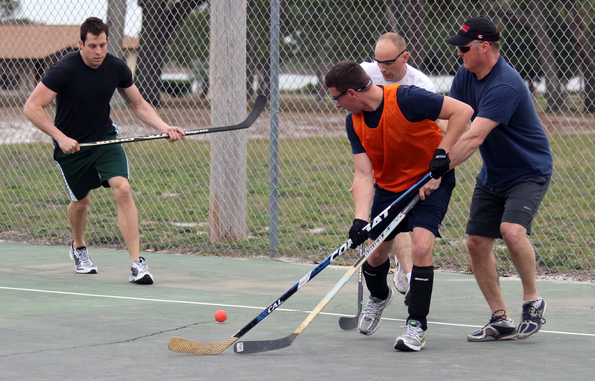 Travis Jardine (orange jersey) of the Tyndall Air Force Base Canadian Detachment team fights for the ball with members of the Royal Canadian Air Force’s 409 Squadron team during a game of street hockey Jan. 31. The 409 Squadron, which flies CF-18s, is at Tyndall to participate in Combat Archer training with the 53rd Weapons Evaluation Group. Given the rarity of visits by other Canadian units to Tyndall, the base detachment jumped on the chance to play a friendly game of their national sport with fellow Canadians. (U.S. Air Force photo by Angela Pope) 