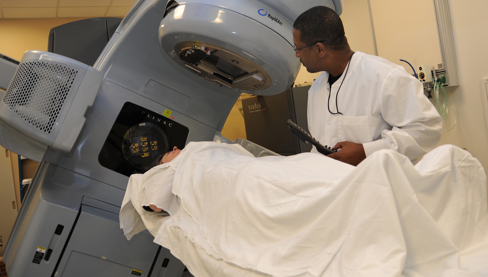 Radiation therapist Rudie Collins demonstrates the position of a patient before beginning a treatment session, Jan. 31, at David Grant USAF Medical Center radiation therapy clinic. (U.S. Air Force photo/ Staff Sgt. Liliana Moreno)