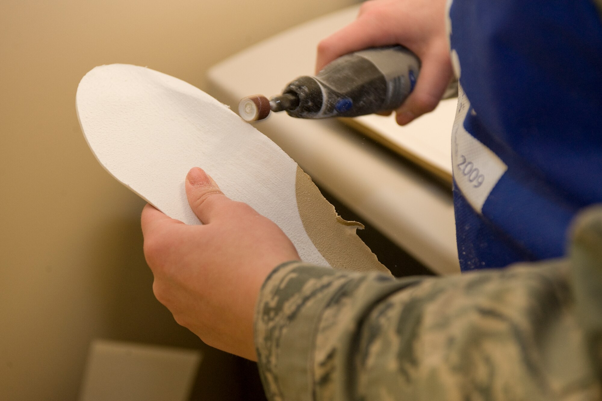 Senior Airman Haylley Carlson, 28th Medical Operations Squadron physical therapy technician, uses a dremel to shave down a foot insole for a proper fit at the physical therapy center on Ellsworth Air Force Base, S.D., Jan. 26, 2012.  The physical therapy center’s orthotic production system provides qualified patients with custom foot insoles.  (U.S. Air Force photo by Airman 1st Class Anania Tekurio/Released)   