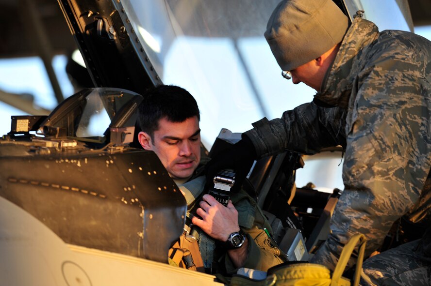 SHAW AFB - Capt. Kyle Crosby, a member of the 77th Fighter Squadron at Shaw AFB, S.C. and a native of Columbus, Ohio gets receives help strapping into his F-16's from Airman 1st Class Ryan McCanna, crew chief assigned to 77th Maintenance Squadron before take-off procedures during an Operational Readiness Exercise at Shaw AFB, SC on Jan. 31, 2012.    (U.S.  Air Force photo/Master Sgt. Cohen A. Young)