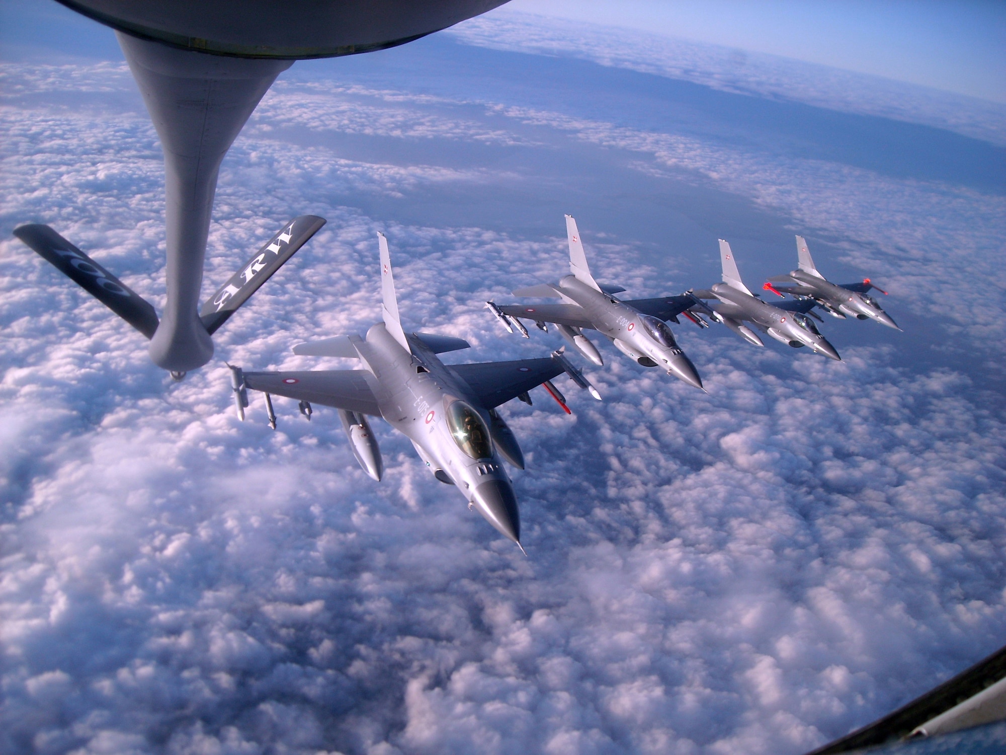 RAF MILDENHALL, England - An 100th Air Refueling Wing KC-135 Stratotanker prepares to offload fuel to Royal Danish Air Force F-16 Fighting Falcons, which are flying in formation behind the tanker. The 100th ARW arrived at RAF Mildenhall Feb. 1, 1992, and has supported U.S. and partner nation military aircraft over a span of more than 20 million square miles using its 15 assigned KC-135 Stratotankers. (U.S. Air Force photo/Tech. Sgt. Kevin Wallace)