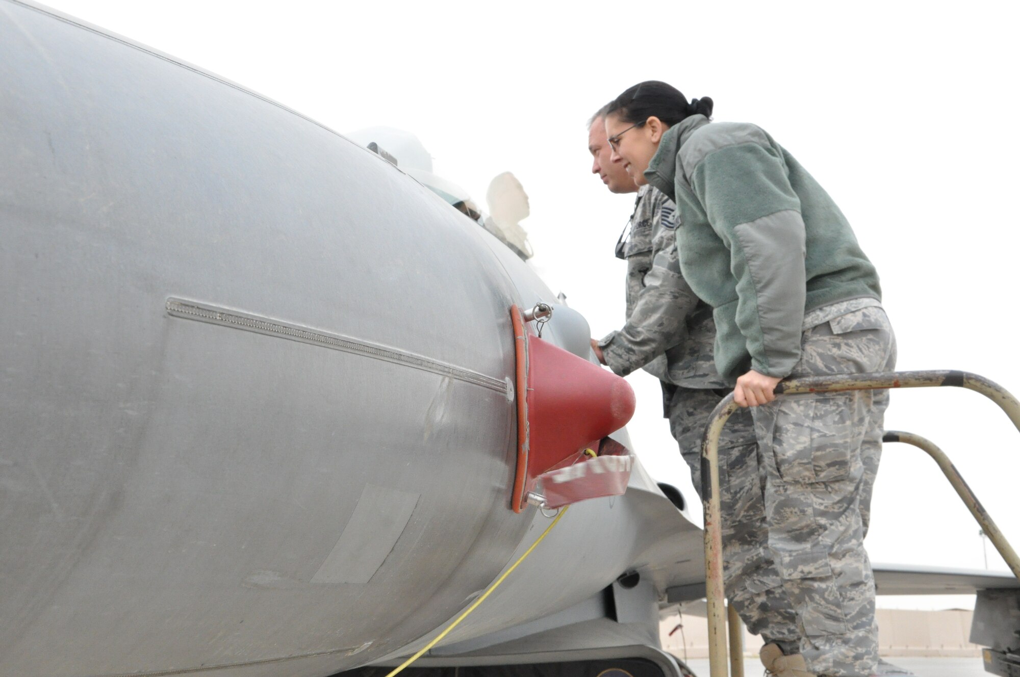 Master Sgt. Ralph Tomeo and Senior Airman Kindra Milligan, 332nd Air Expeditionary Wing staff agency members, peak inside the cockpit of an F-16 during a maintenance tour Jan. 31, 2012 at an undisclosed location in Southwest Asia. Milligan is deployed from Moody Air Force Base, Ga., and is a native of Oklahoma City. Tomeo is deployed from Joint Base McGuire Dix Lakehurst, N.J., and is a native of East Patchogue, N.Y. (photo by Senior Airman Melanie Holochwost)