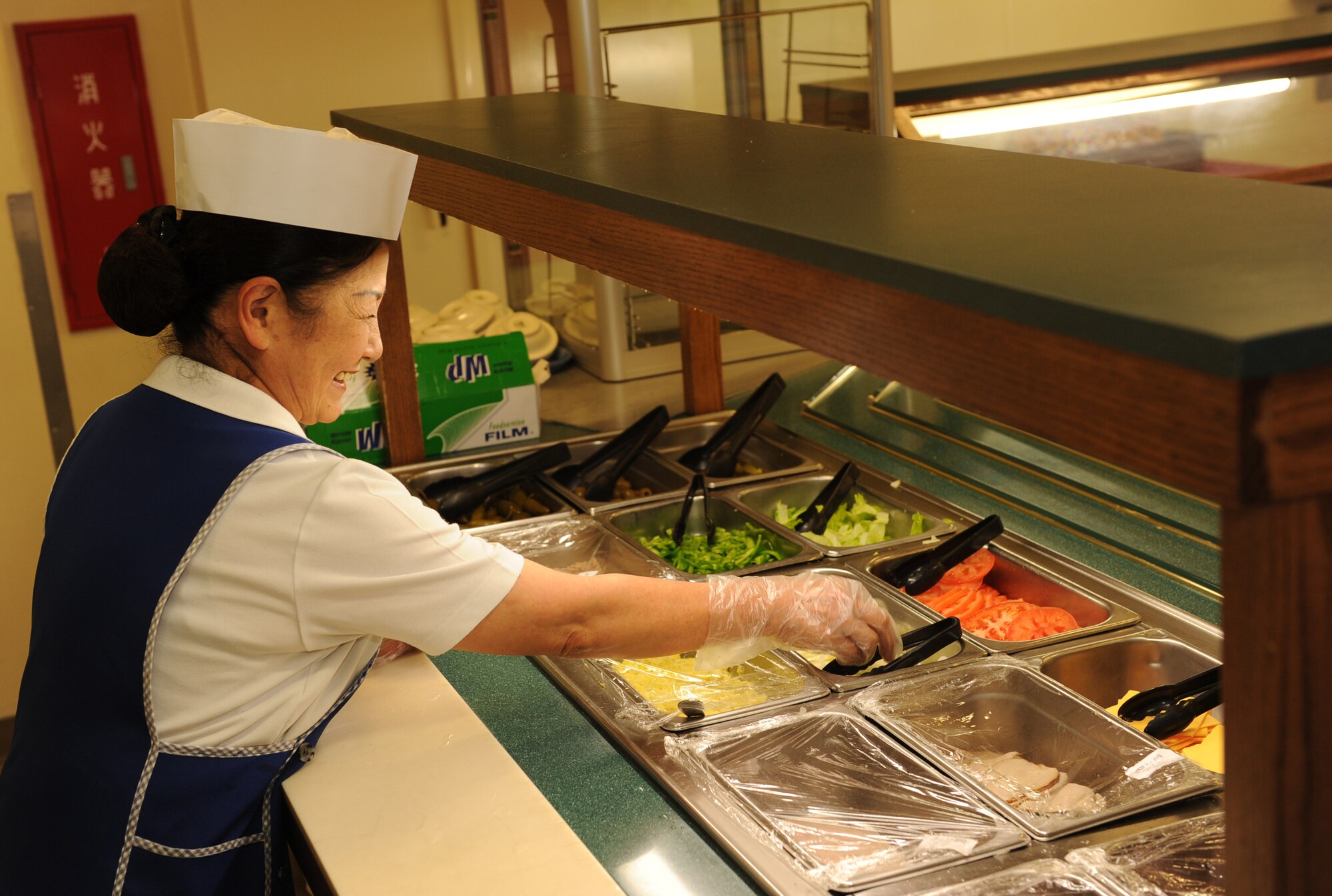 Mitsue Tamashiro, 18th Force Support Squadron sales checker, stocks the salad bar at the Marshall Dining Facility on Kadena Air Base, Japan, Feb. 1, 2012. The 18th FSS's food service team has been selected by Pacific Air Forces to represent the command in the Air Force competition for the 2012 John L. Hennessy Trophy in the multiple facility category. (U.S. Air Force photo by Airman 1st Class Justin S. Veazie/Released)