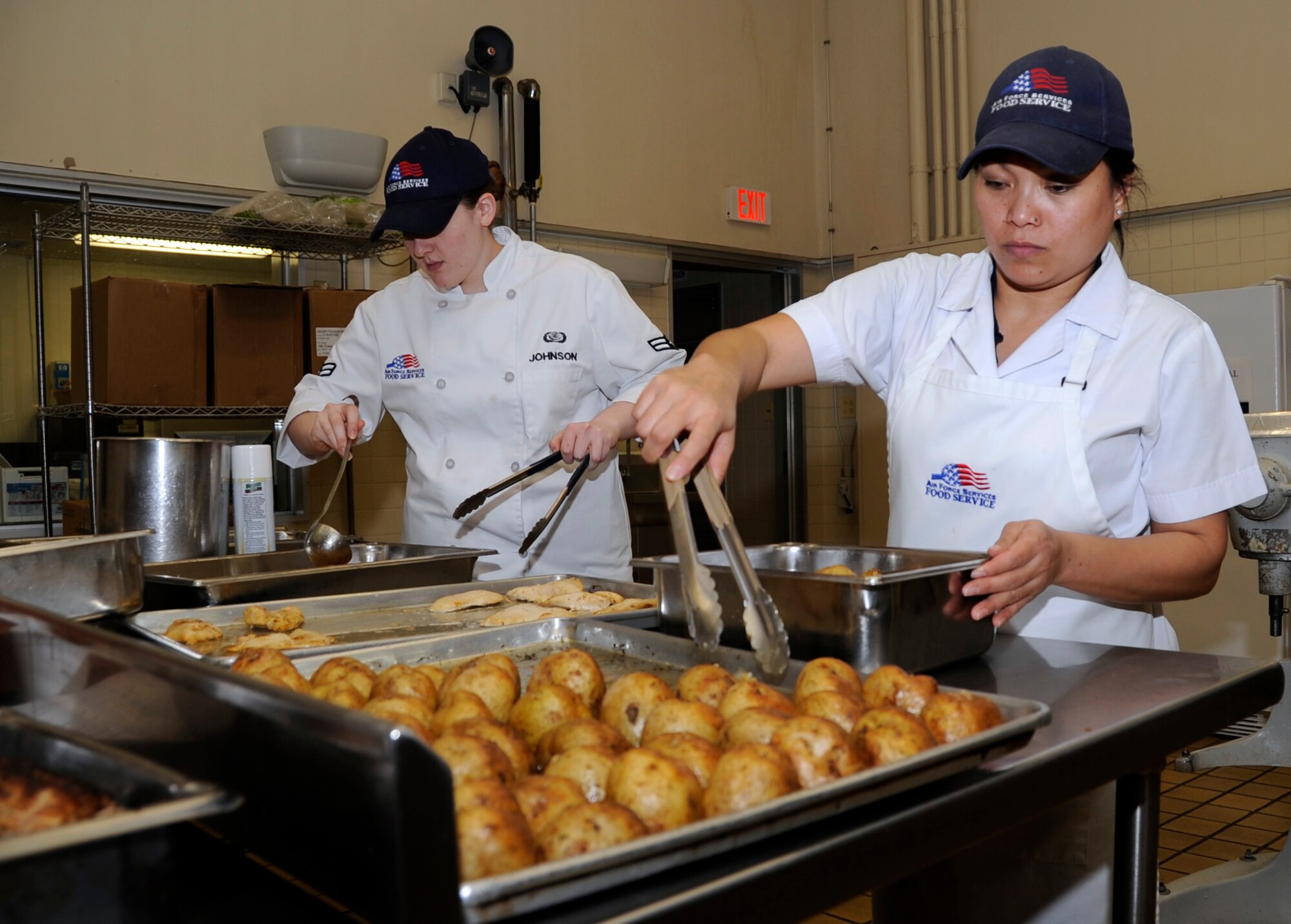 MISAWA AIR BASE, Japan -- Airman 1st Class Ragen Johnson, 35th Force Support Squadron food service apprentice, right and Raquel Suzuki, 35th Force Support Squadron contract cook, bake chicken and potatoes at Grissom Dining Facility here, Jan. 26. On average, $45,000 is spent each month on food in order to feed servicemembers at the DFAC.  (U.S. Air Force photo/Airman 1st Class Kaleb Snay)