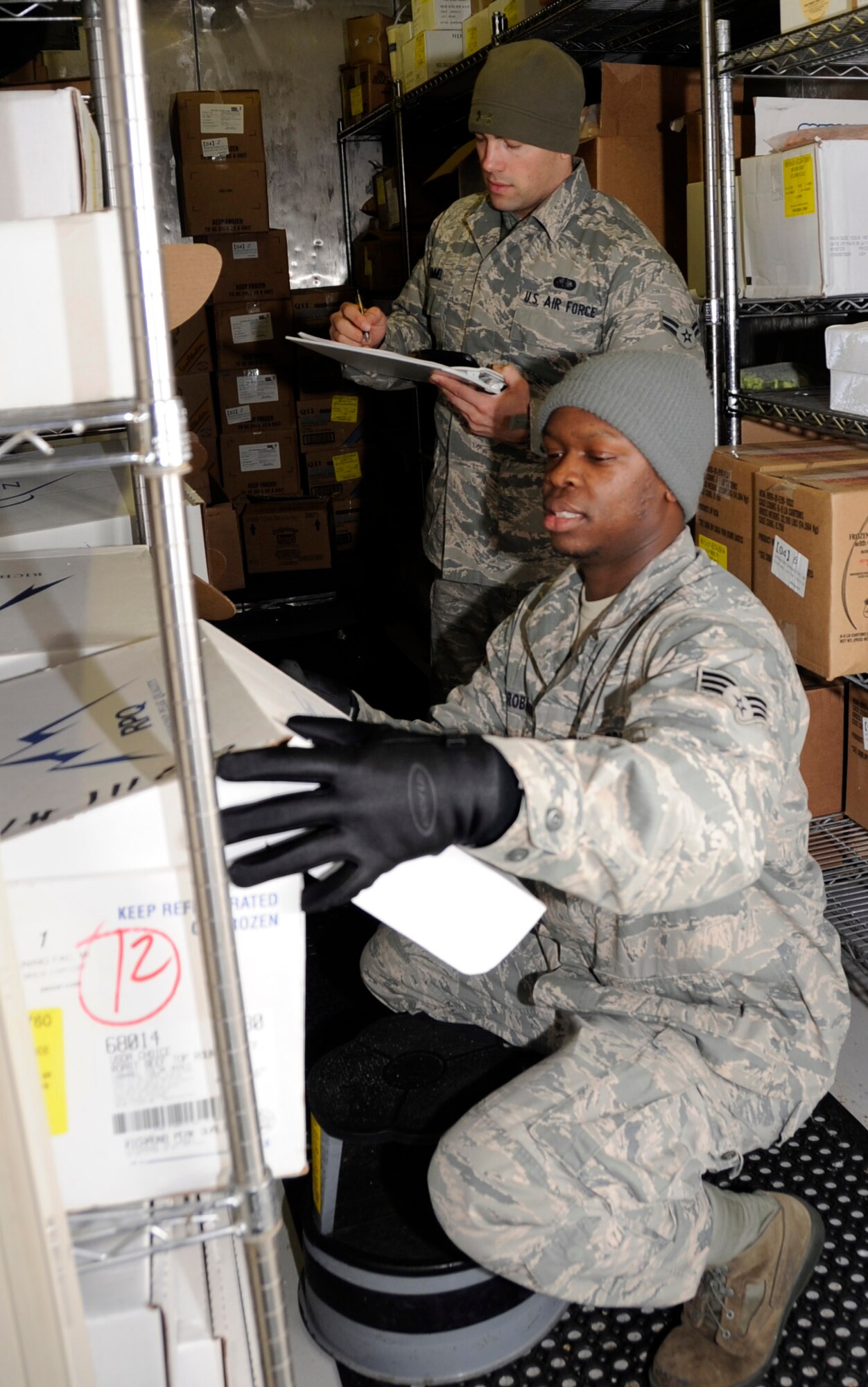 MISAWA AIR BASE, Japan -- Senior Airman Raphael Robinson, right and Airman 1st Class Denny Kimmel, 35th Force Support Squadron food service apprentices, check expiration dates on all frozen foods at Grissom Dining Facility here, Jan 26. There is currently a mix of 20 Airmen and civilian contractors who work at the DFAC. (U.S. Air Force photo/Airman 1st Class Kaleb Snay)